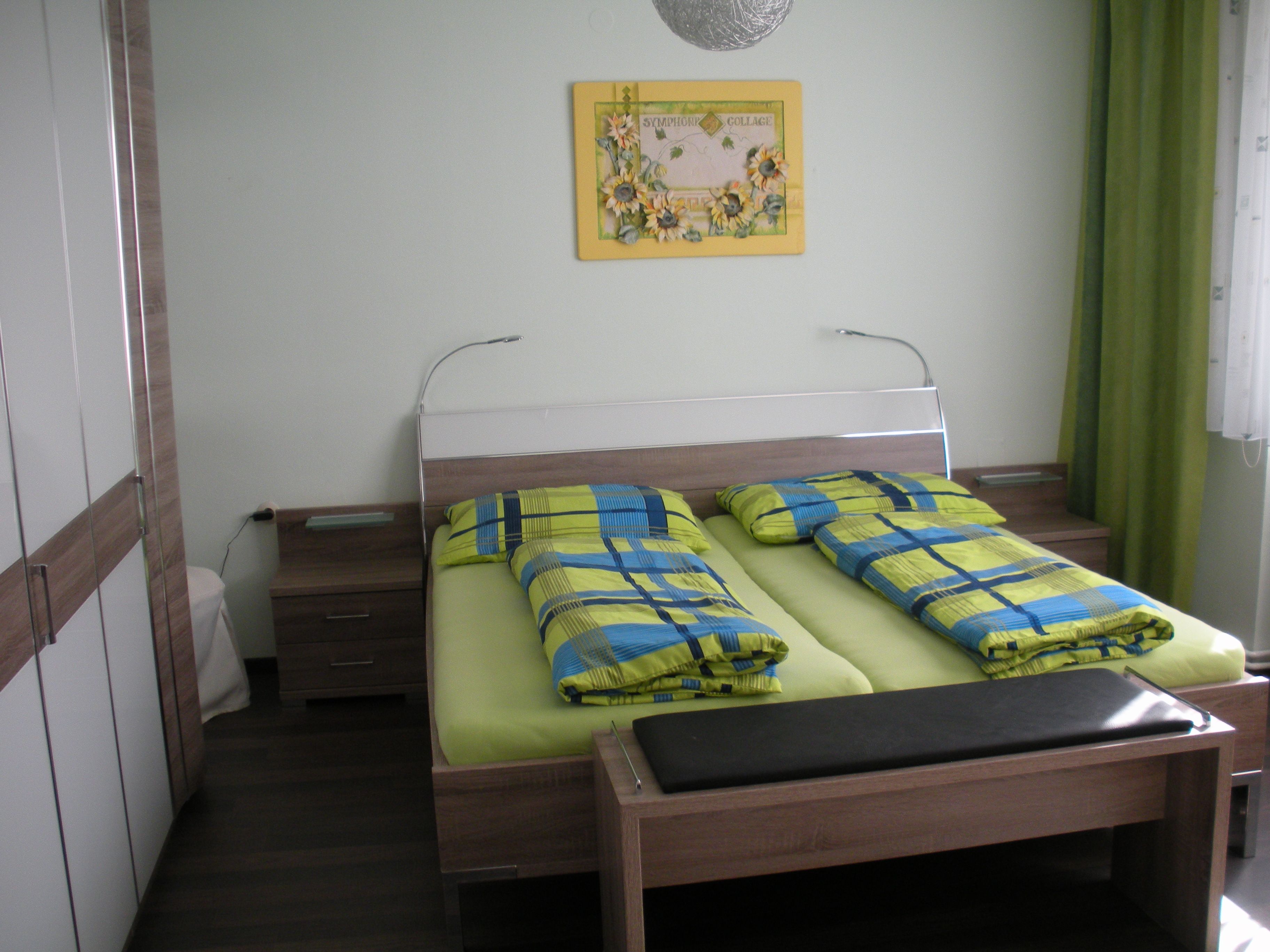 Guest room with double bed, colorful bedding and mural.