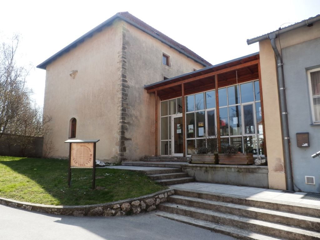 A historic building with a modern extension and a sign in the foreground.