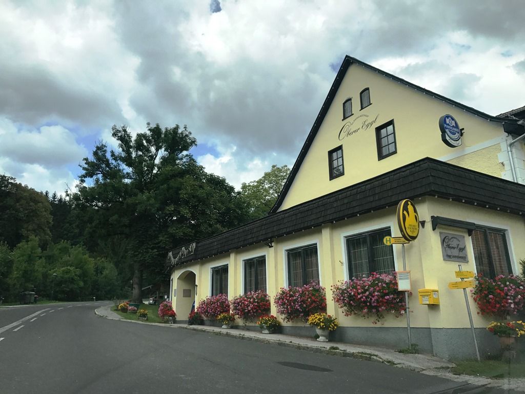 Gasthof Oberer Eggl with flowers and bus stop.
