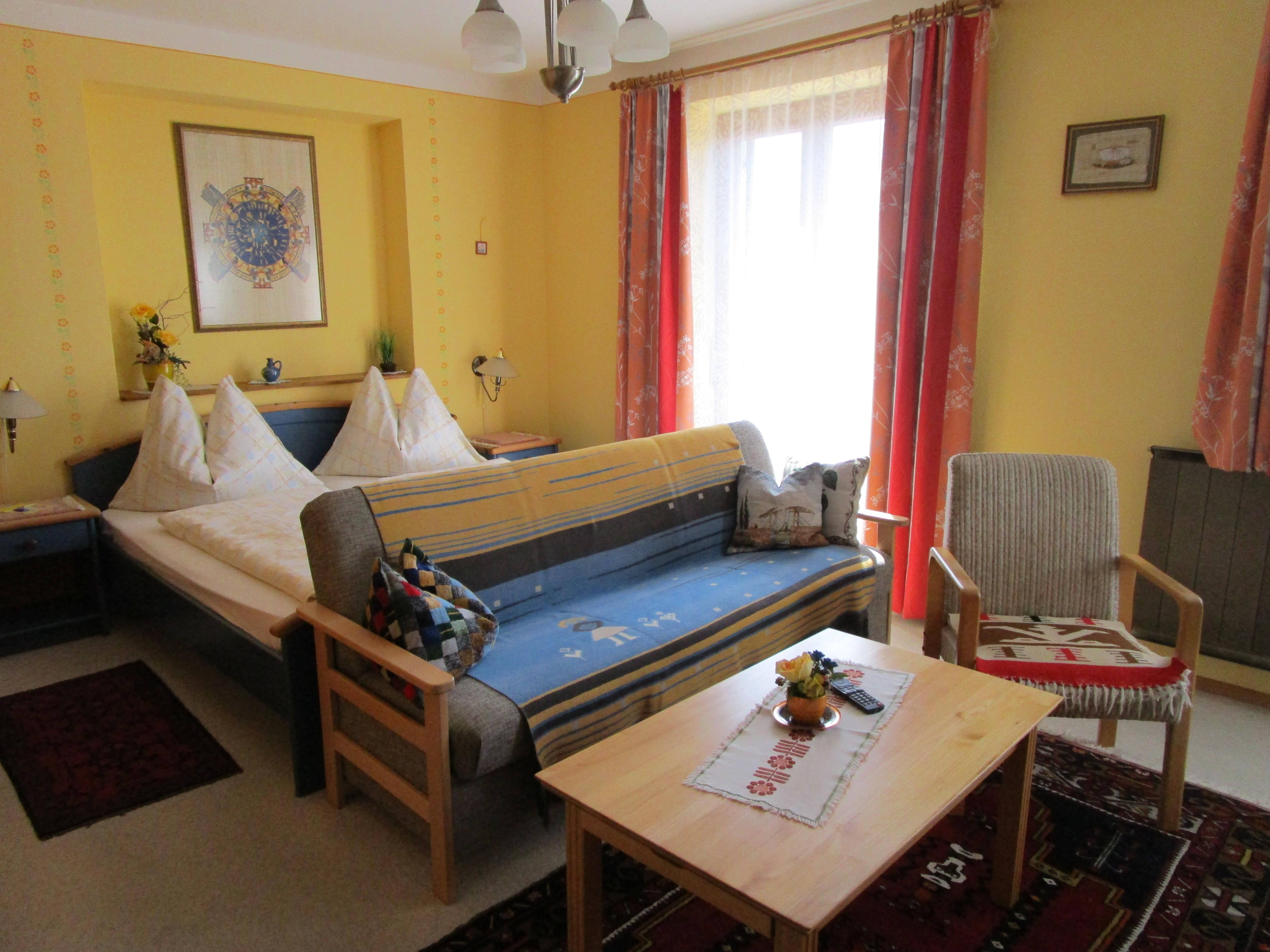 Room with double bed and couch with table in the foreground