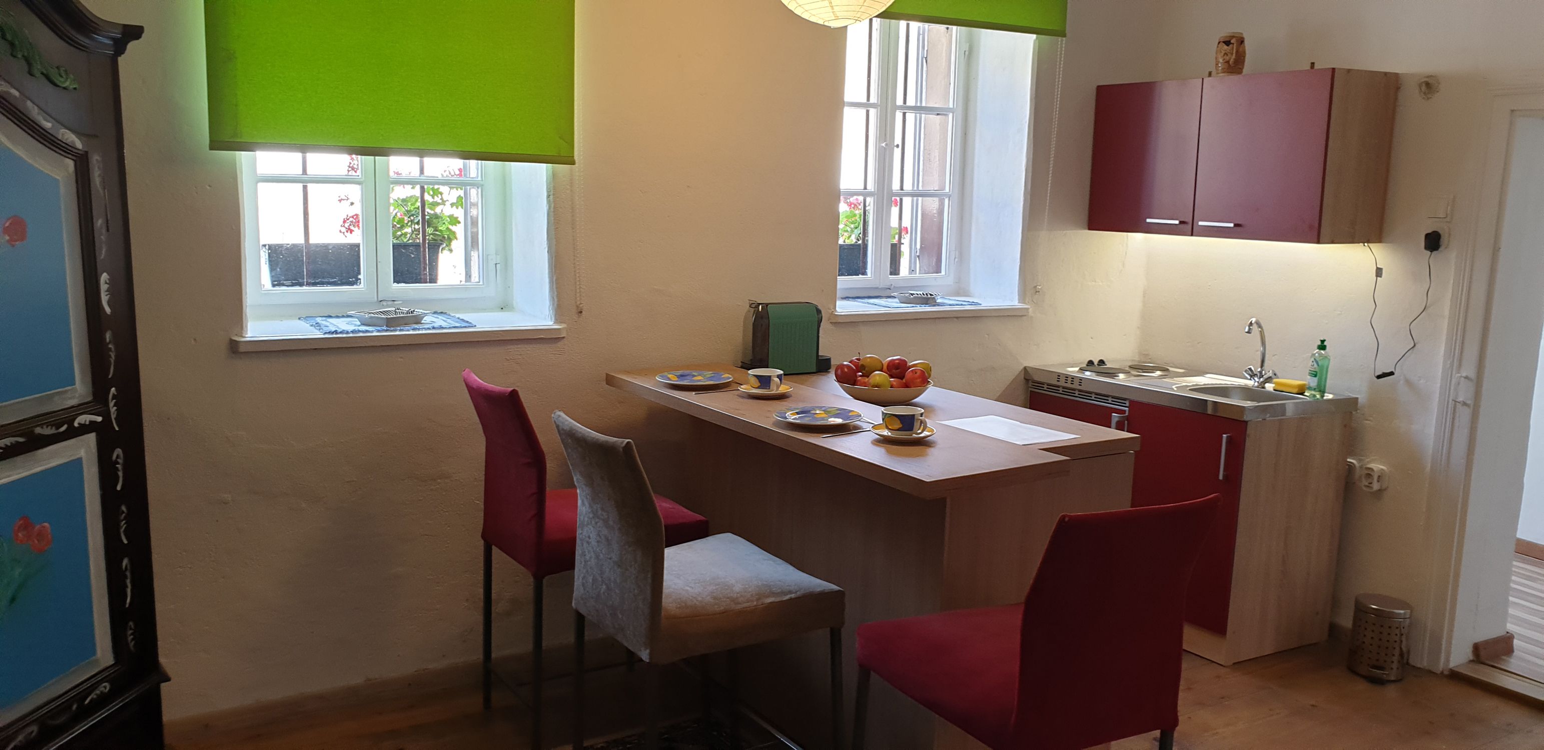 Kitchen with dining table, chairs and window with green blind.