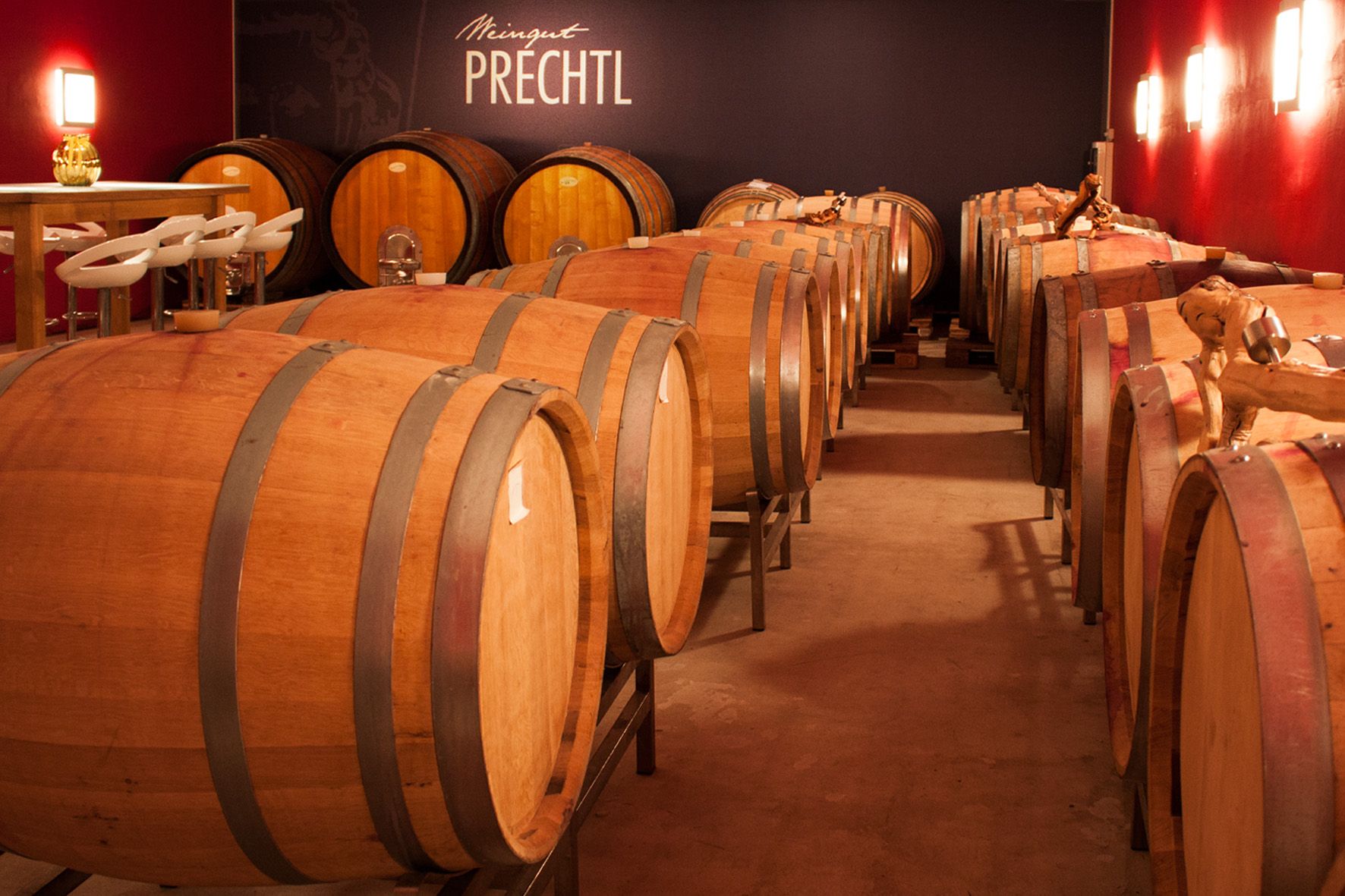 Wine cellar with wooden barrels and table with chairs, Prechtl winery.