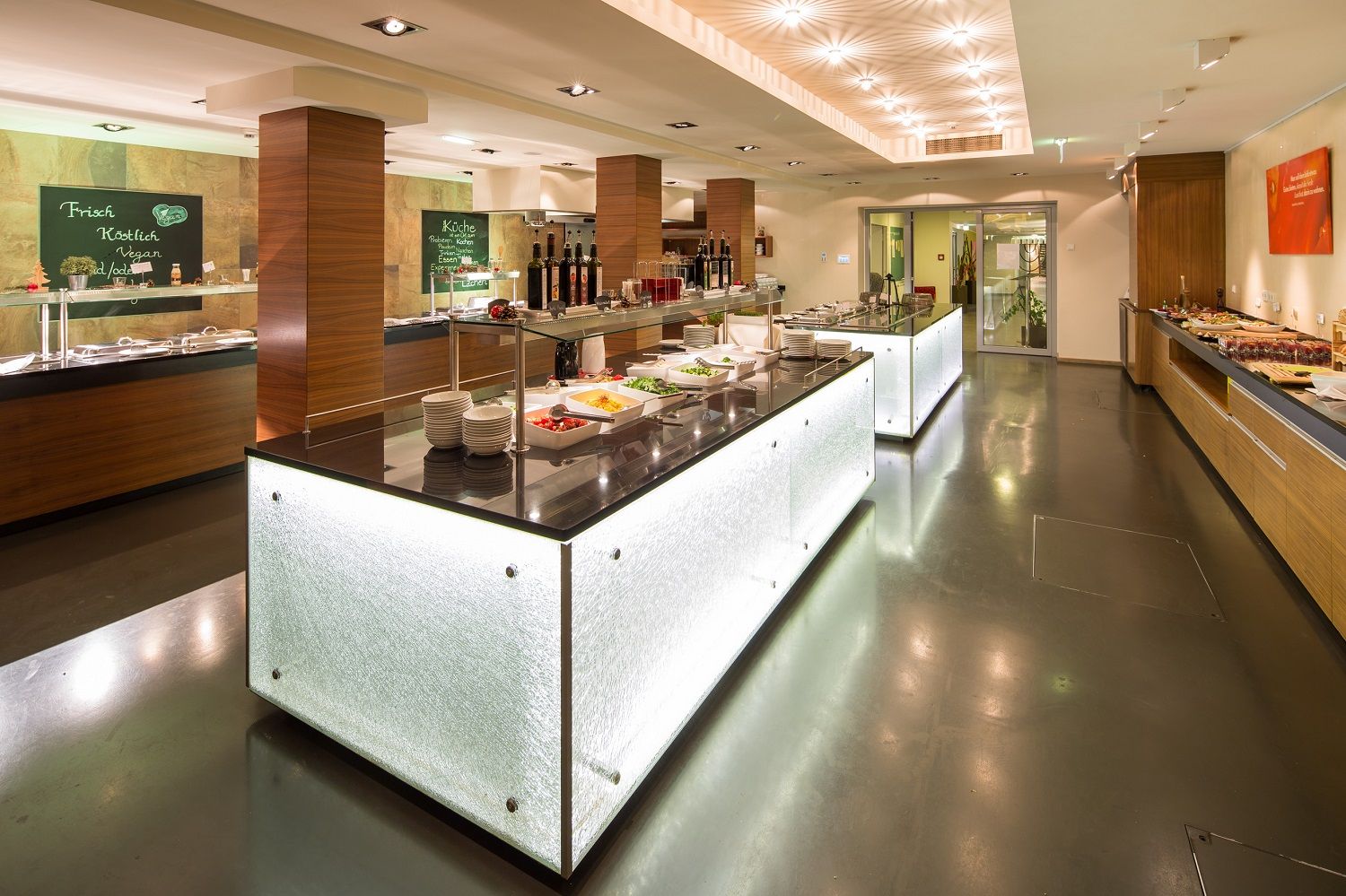 Modern buffet in a hotel restaurant with illuminated counters and various dishes.