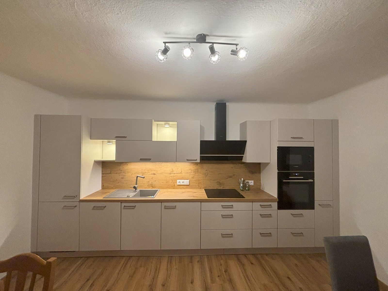Modern kitchen with white cupboards, wooden worktop and built-in appliances.