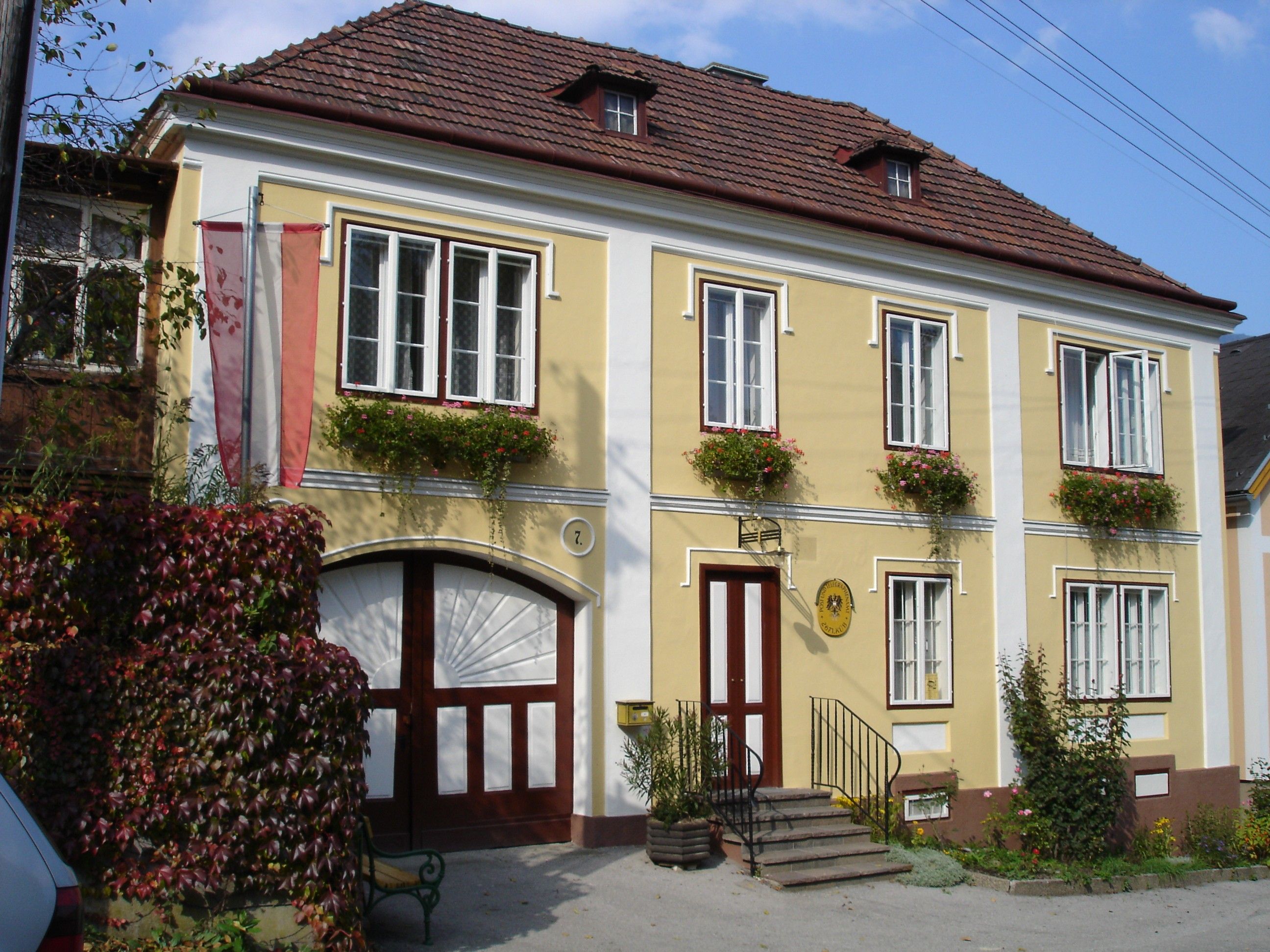 Yellow building with red shutters and flowers, nostalgic Küb post office.