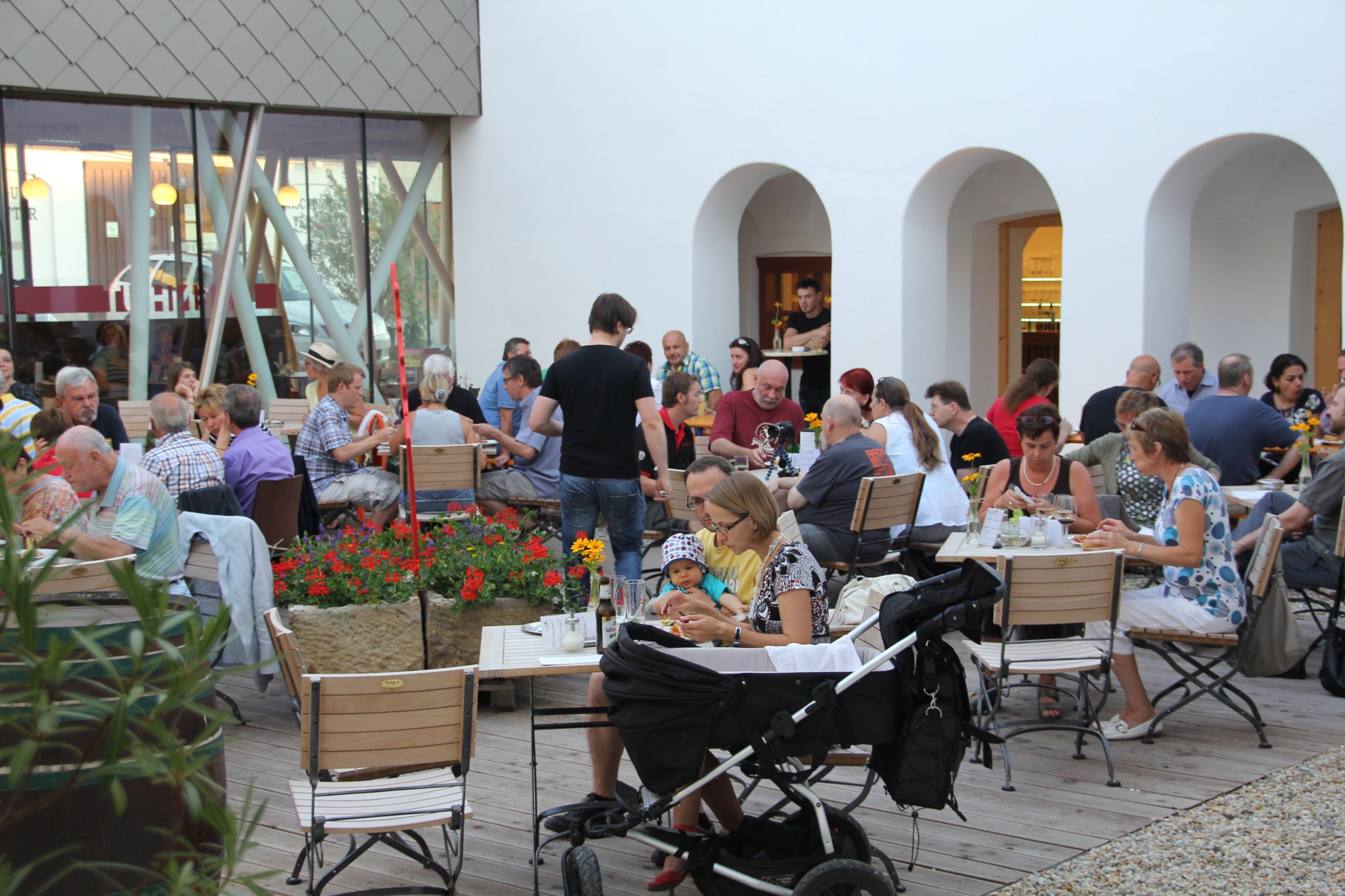 People sit at tables in an inner courtyard and eat.