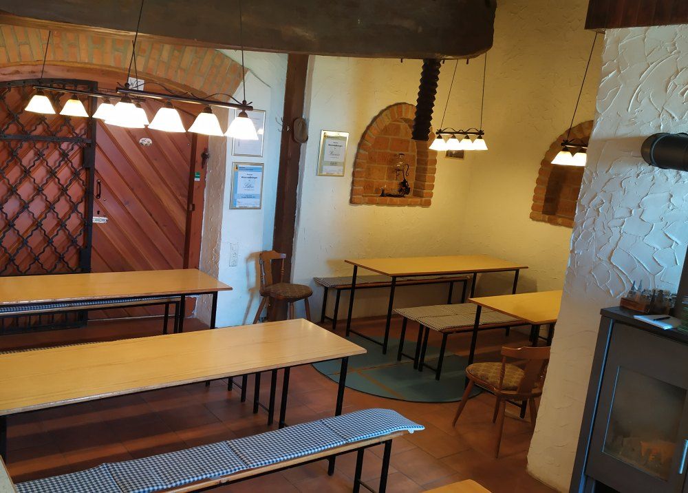Interior view of a wine tavern with wooden tables, benches and rustic decoration.