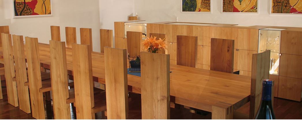 Wooden table with wine glasses in a bright tasting room, simple and inviting ambience for wine tastings.