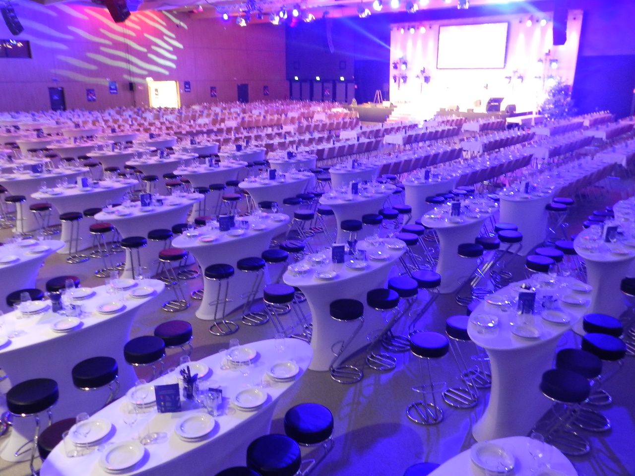 Large hall with covered tables and chairs, illuminated in blue and purple.
