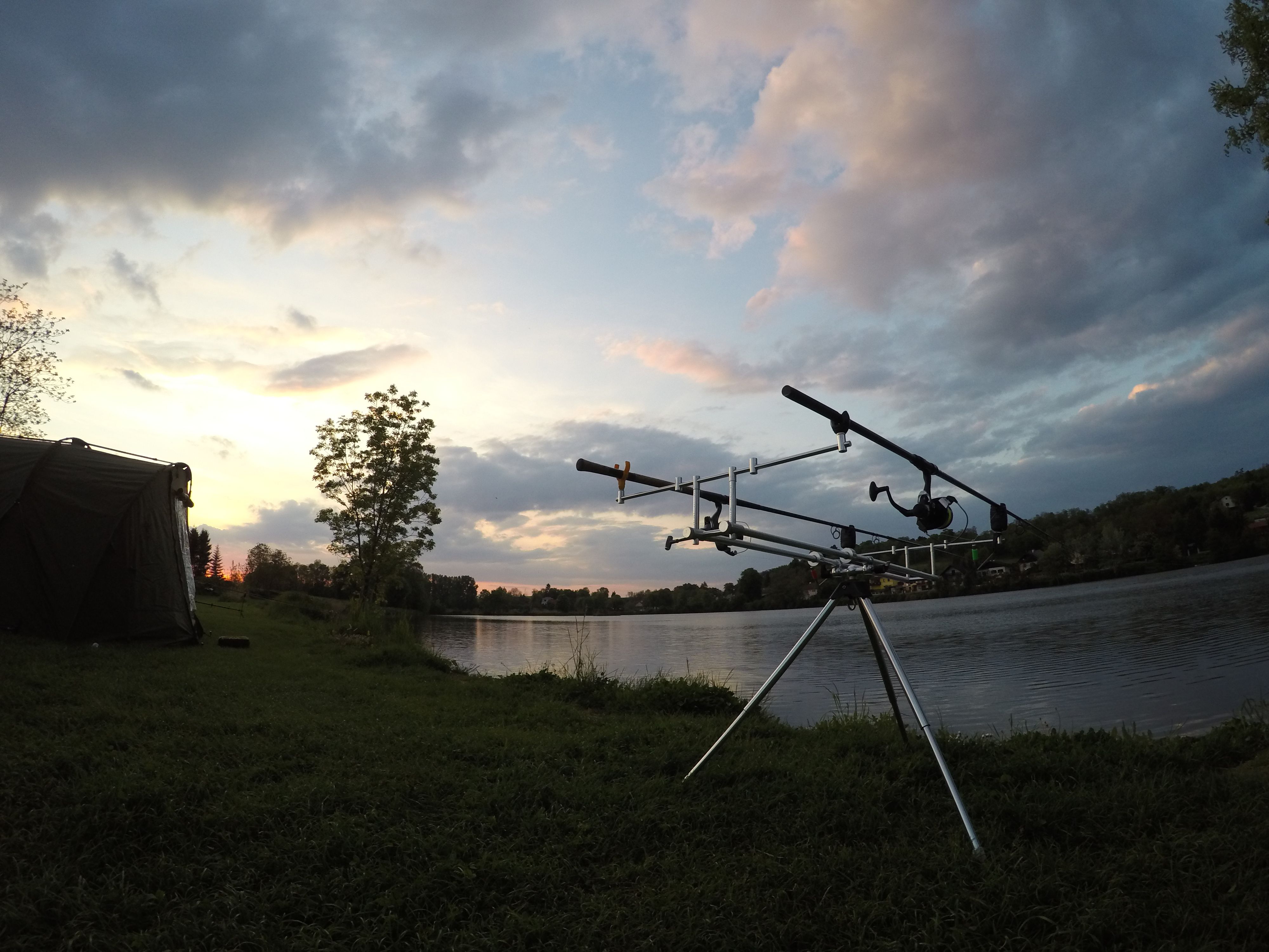 Fishing rods on a stand on the lakeshore at sunset.