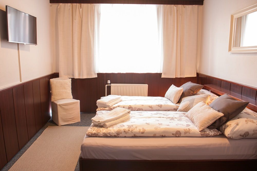 Comfortable hotel room with two single beds, TV, chair and window with curtains.