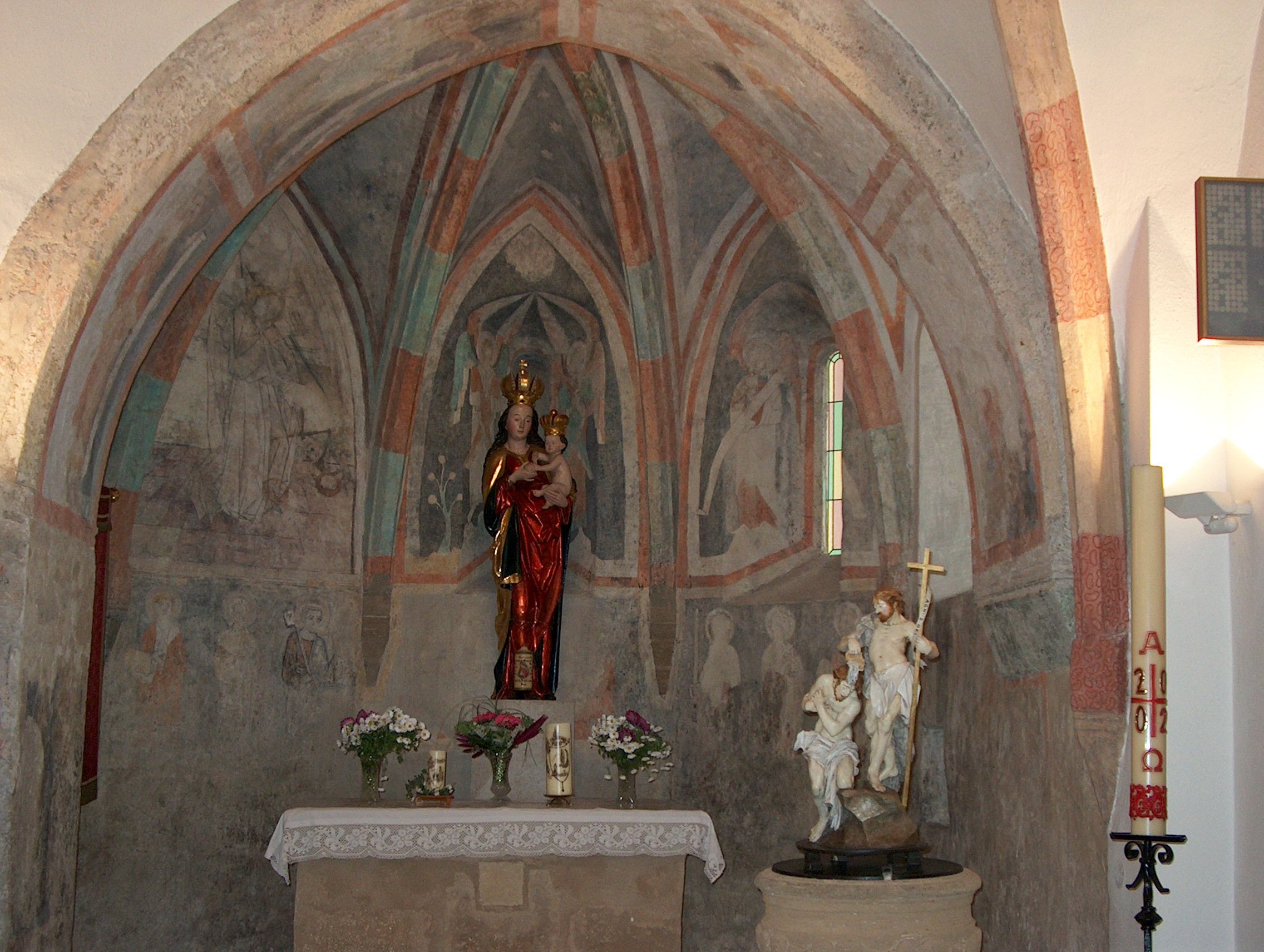 Interior view of a chapel with murals and religious statues.