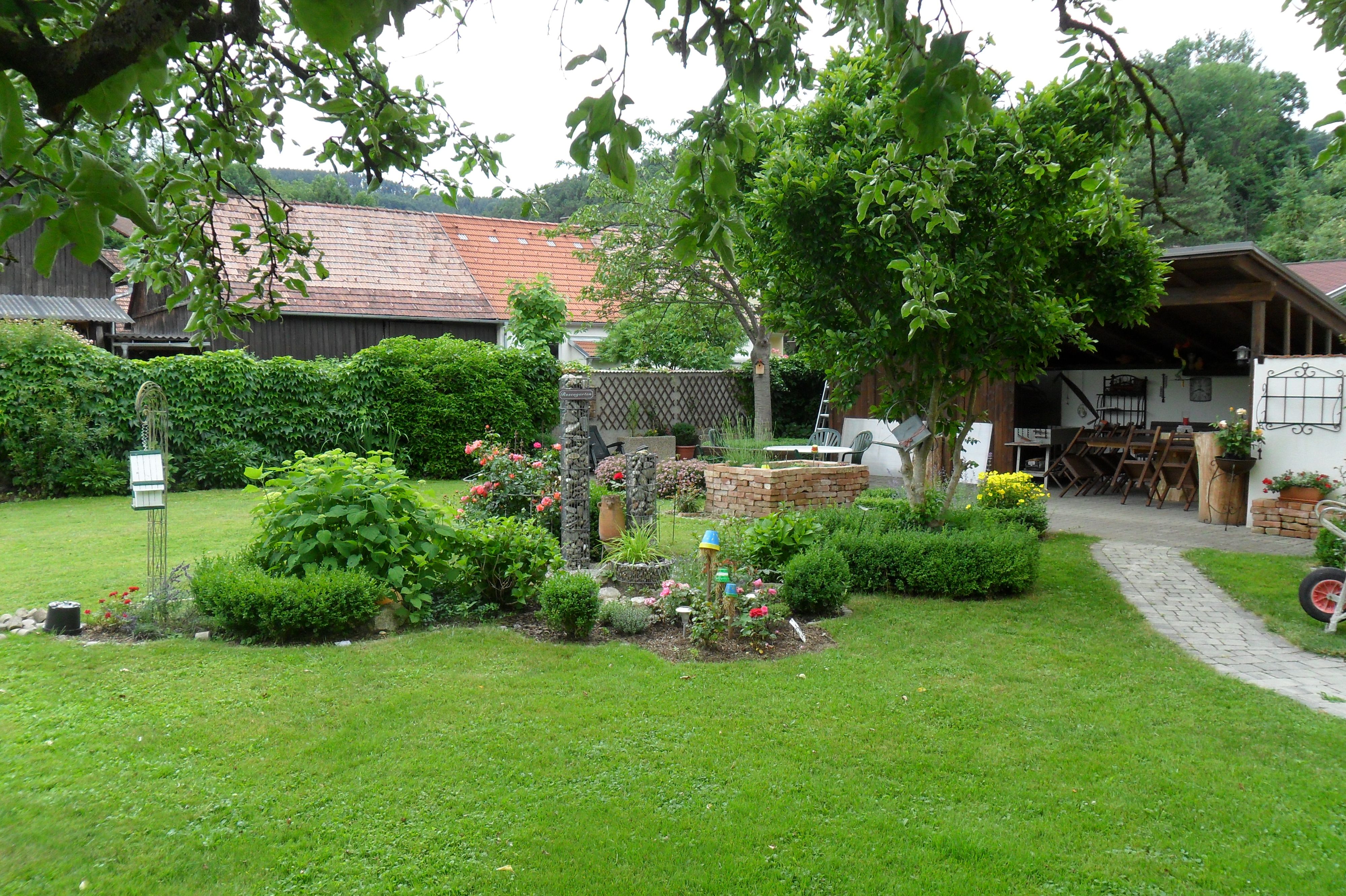 Garden with lawn, flower beds and covered seating area.