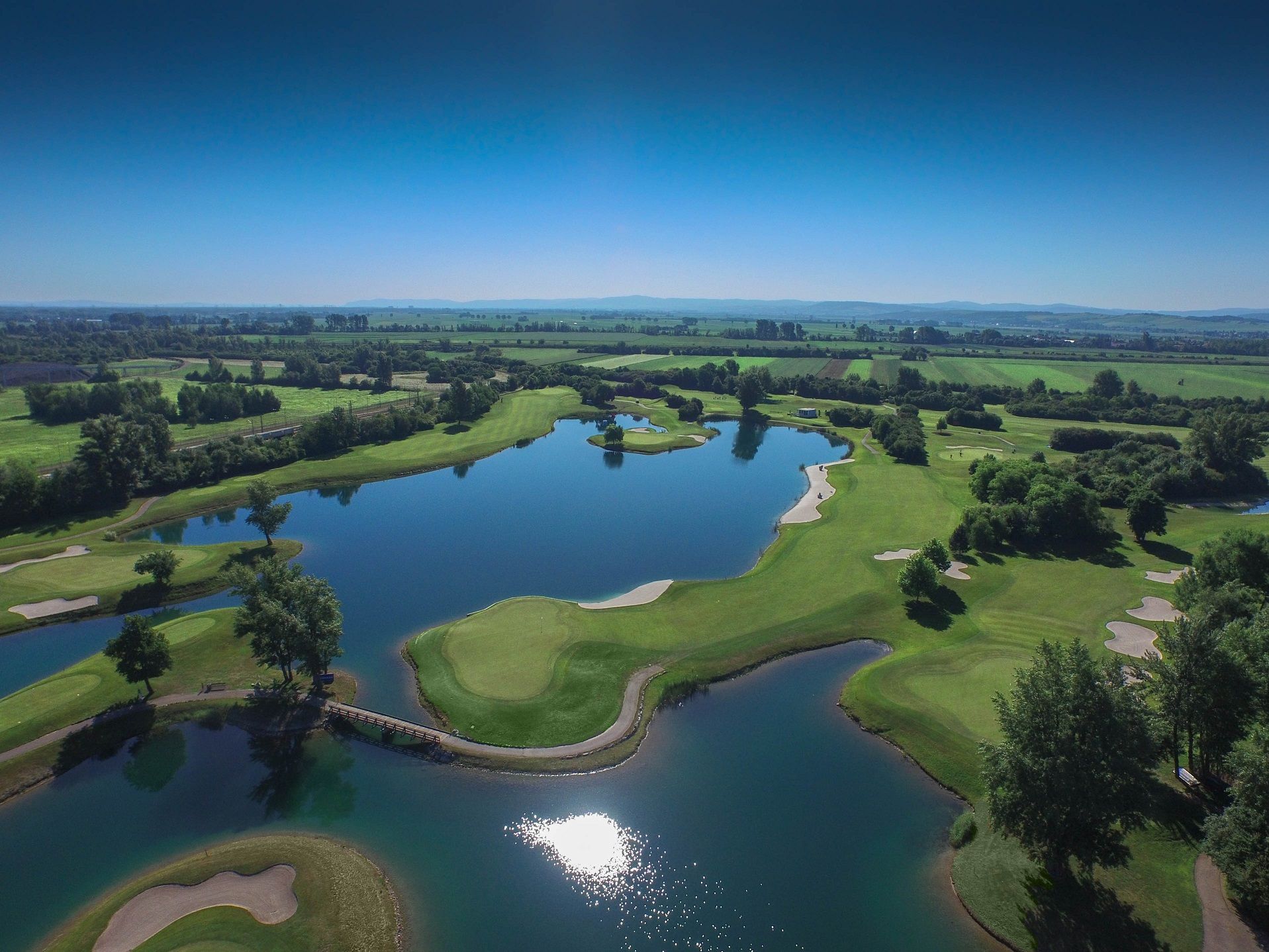 Aerial view of a golf course with water hazards and green fairways.