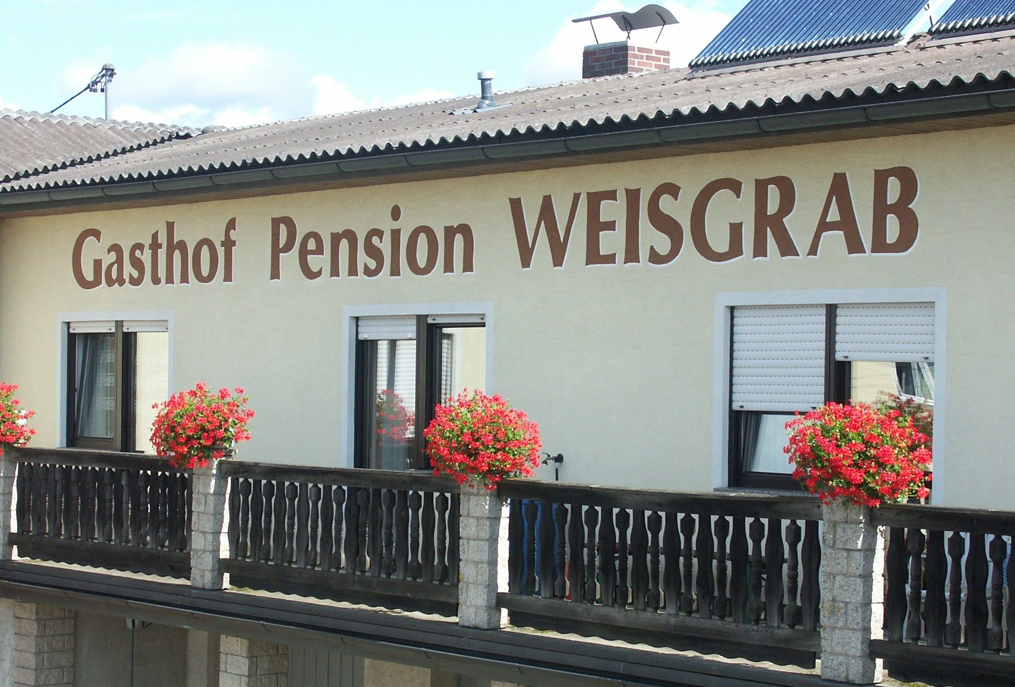 Façade of Pension Weisgrab with flower boxes on the balcony.