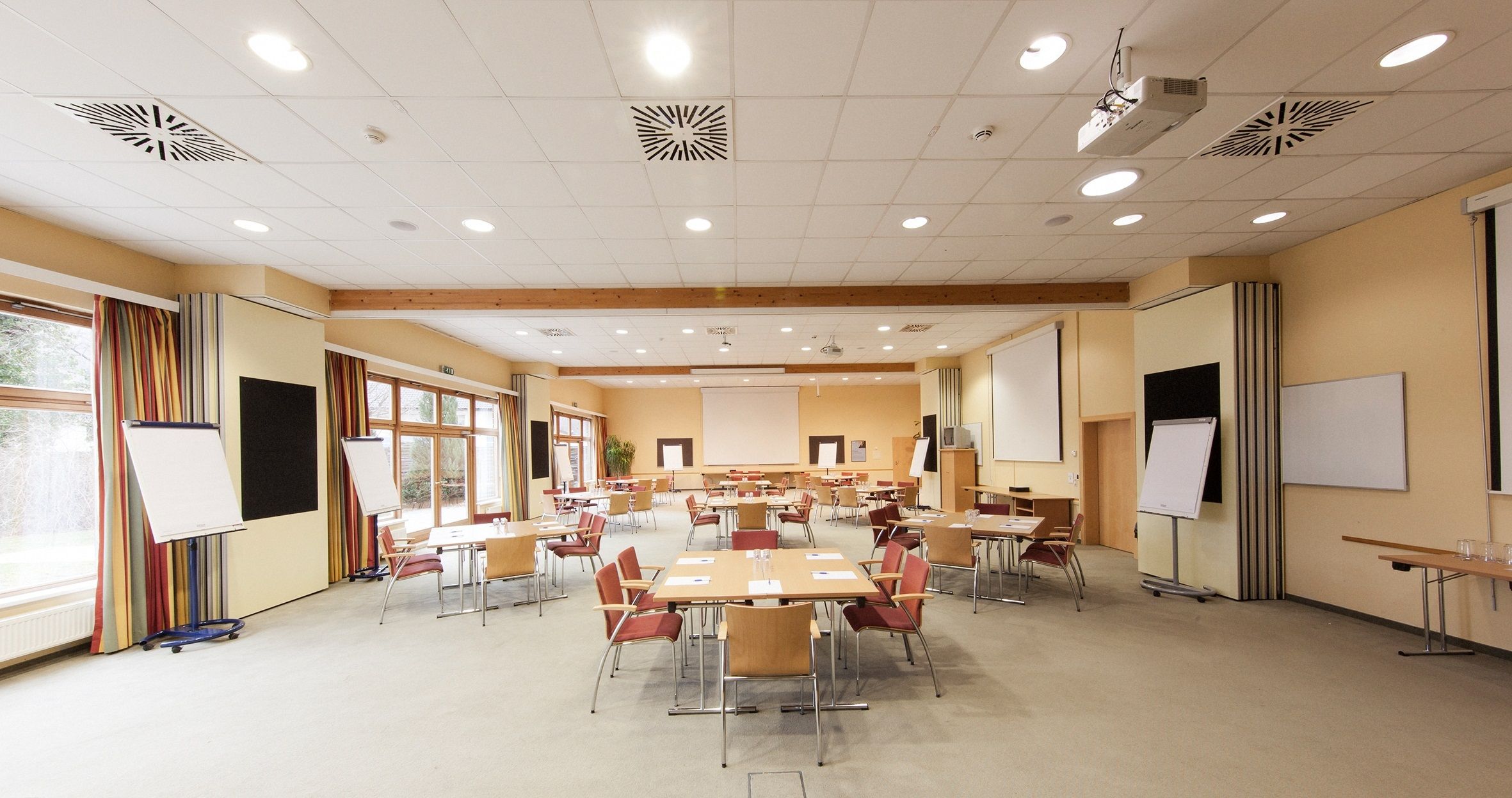 An empty conference room with tables, chairs and flipcharts.