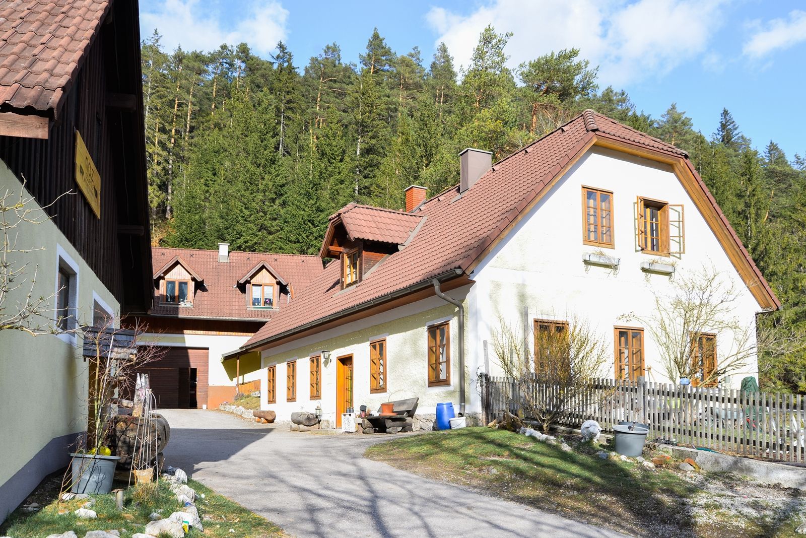 A traditional farmhouse with red roofs in front of a forest.
