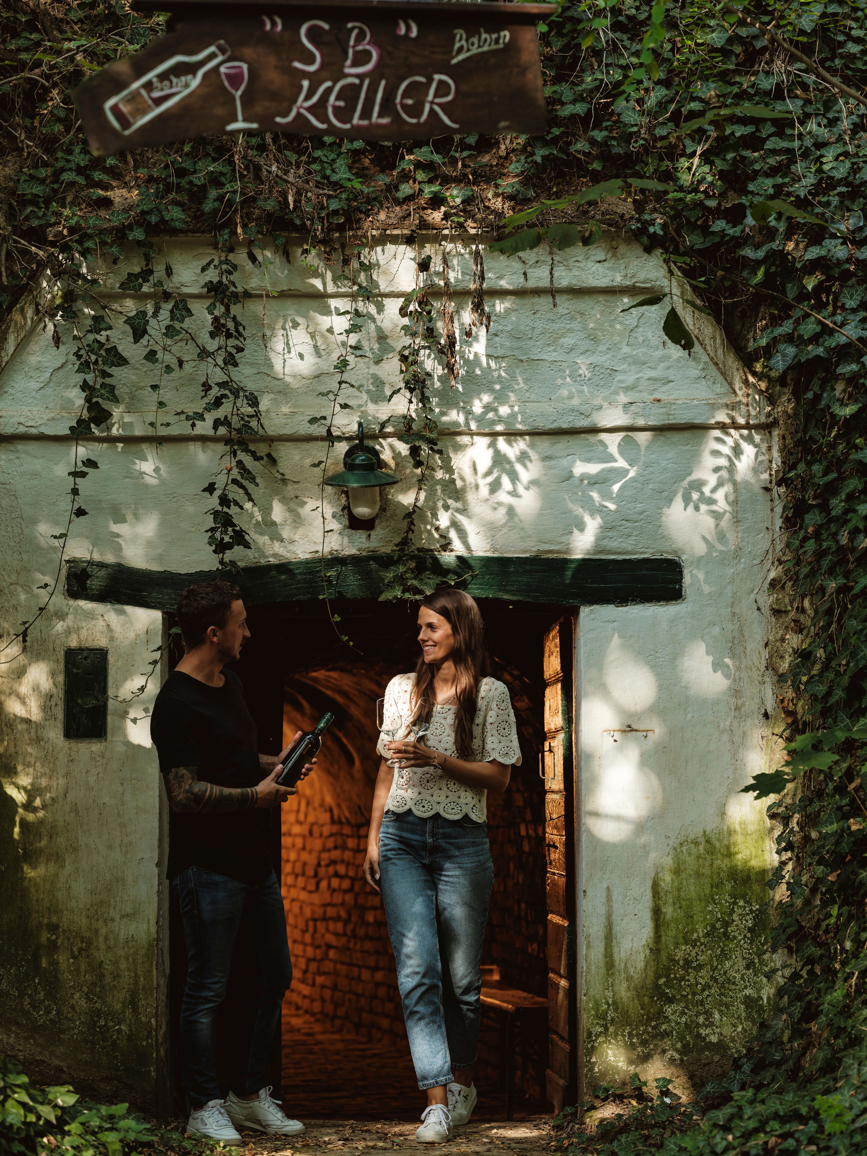 Two people are standing in front of a wine cellar on Schindergasse in Herrnbaumgarten.