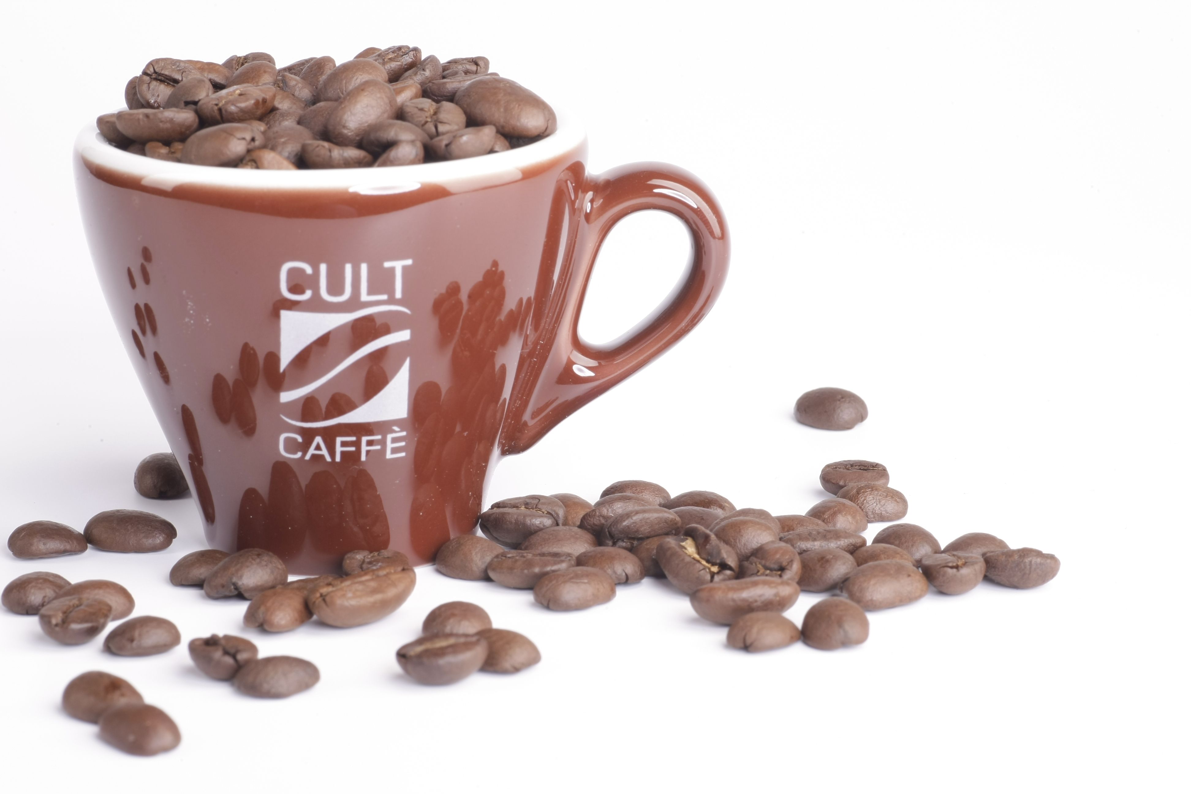 Brown cup with the inscription 'Cult Caffè', filled with coffee beans, on a white background.