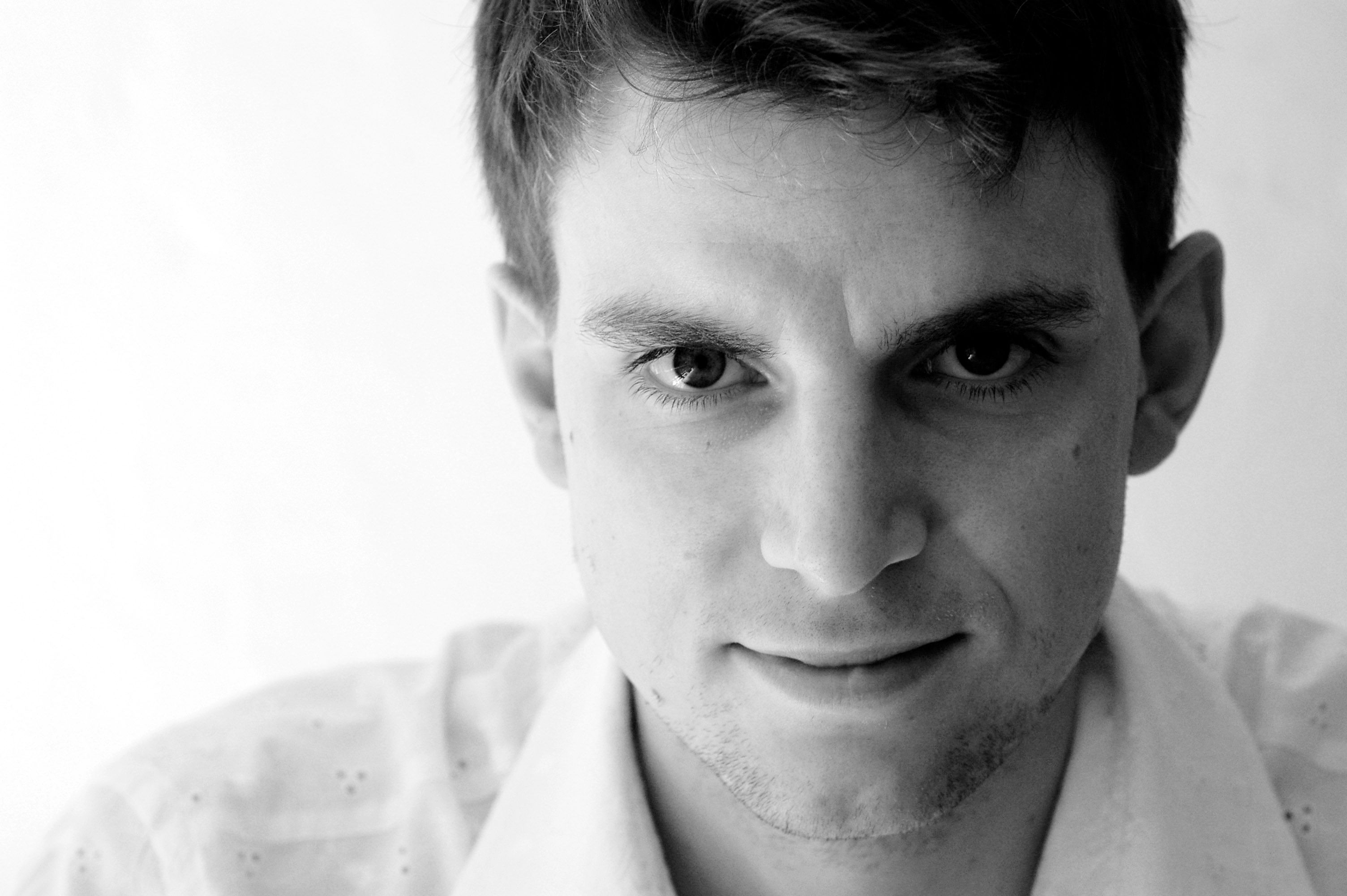 Black and white portrait of a young man with short hair and a serious look.