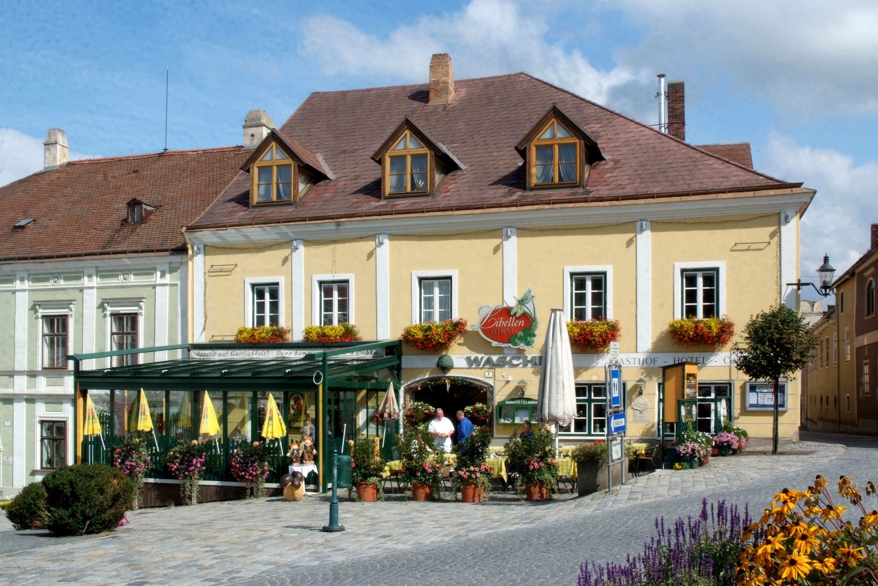 A traditional inn with a yellow façade and floral decorations.