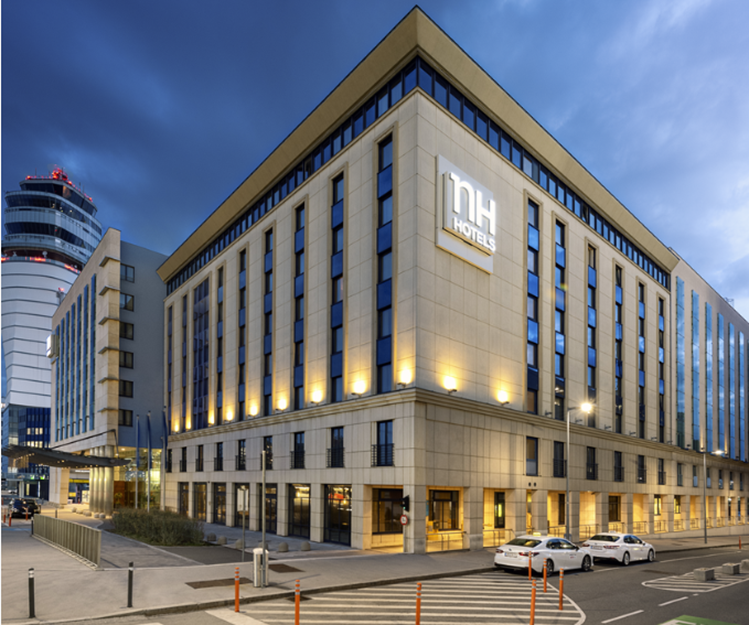 NH Vienna Airport Conference Center at dusk with illuminated building.