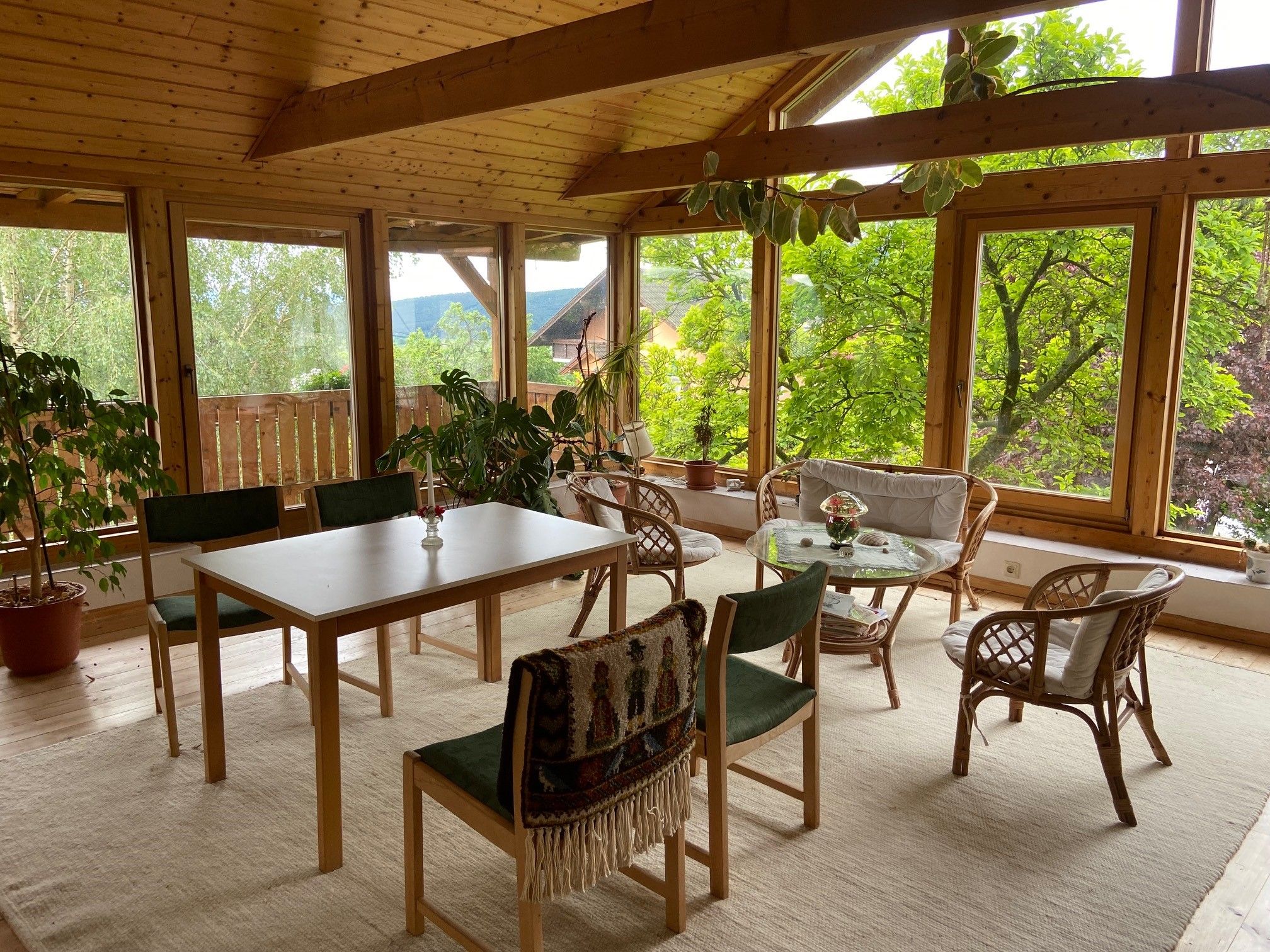 A bright room with wooden furniture, large windows and plants.