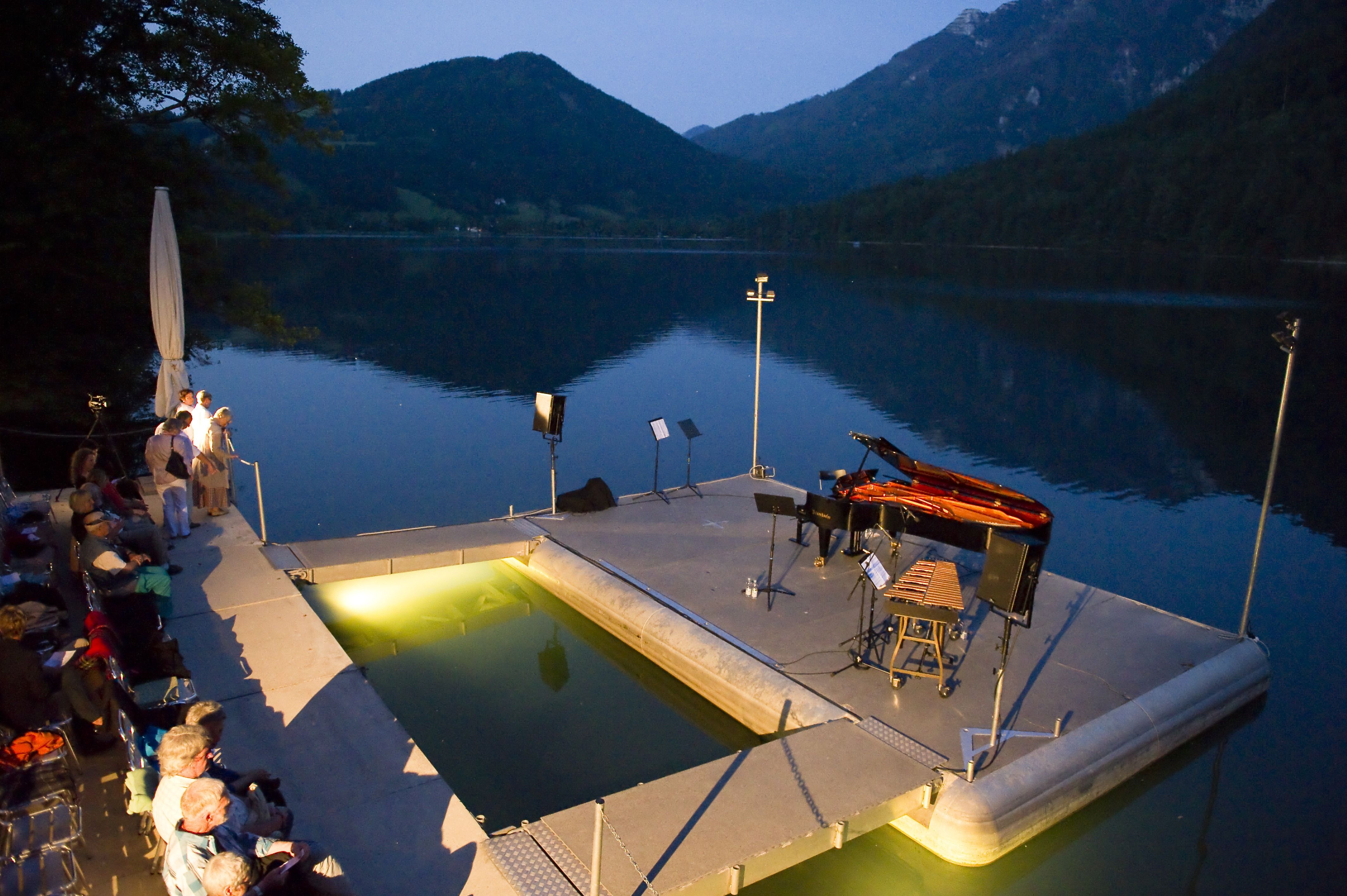 Lunz am See lake stage at dusk with piano and spectators.