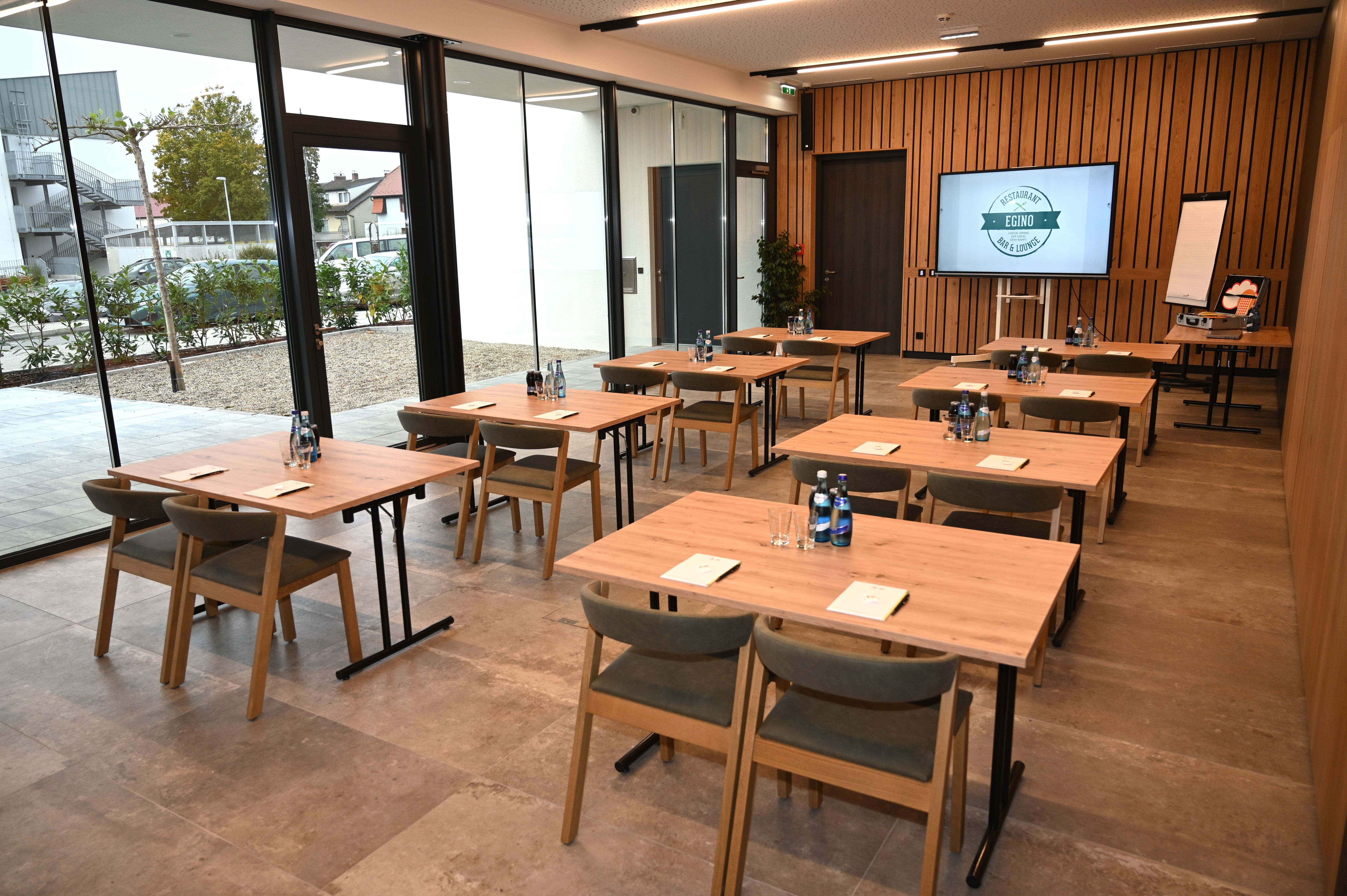 Modern seminar room with wooden tables, chairs and presentation technology.
