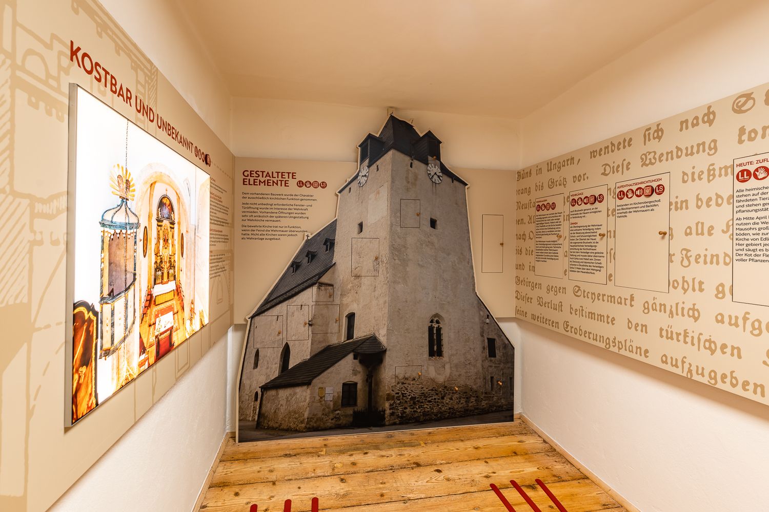 Interior view of an exhibition on fortified churches with text panels and a floor-to-ceiling picture of a church.