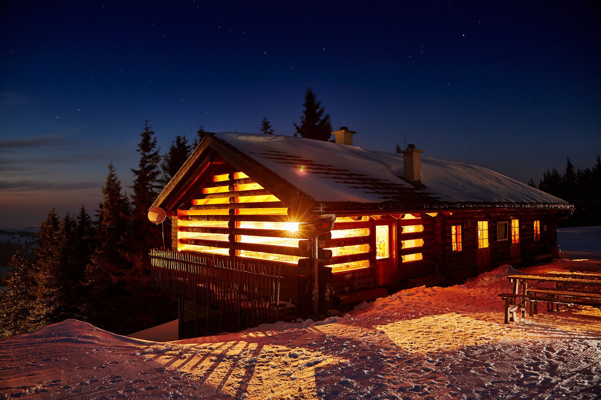 In der winterlichen Stille erstrahlt die Anna Alm in warmem Licht, während der Schnee sanft die Umgebung bedeckt. Die gemütliche Hütte lädt dazu ein, nach einem aufregenden Skitag am Hennesteck zu verweilen und die atemberaubende Aussicht auf die verschneiten Berge zu genießen.