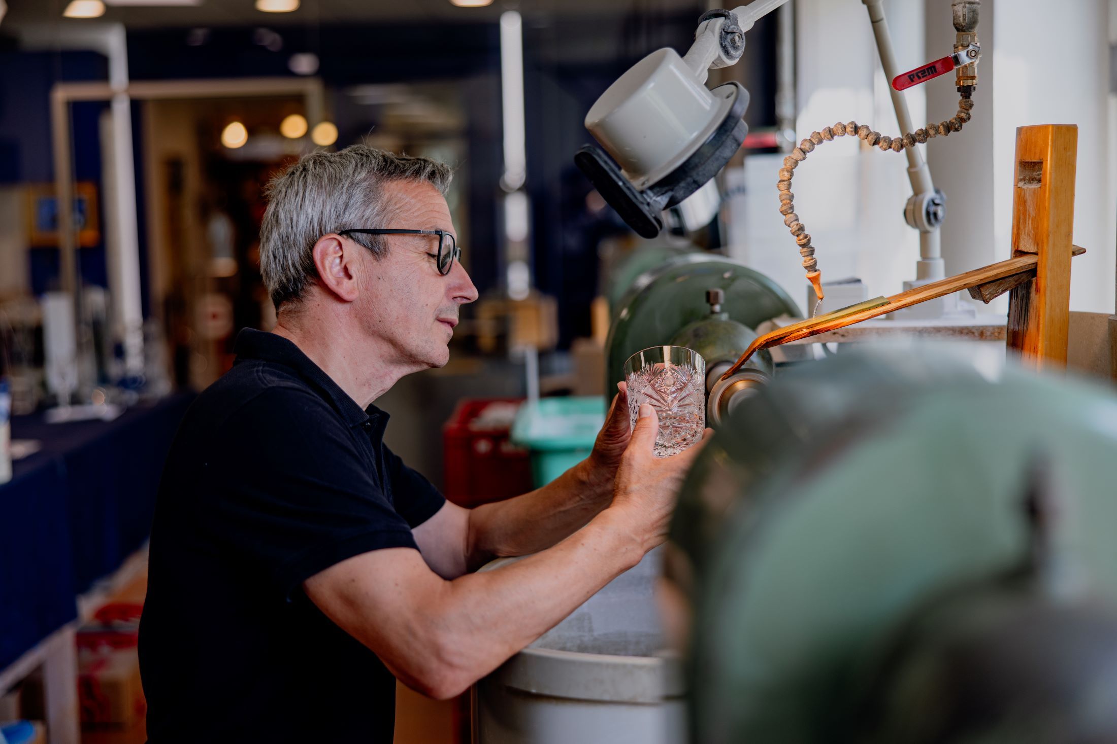 A man works on a glass at a grinding machine in a workshop.