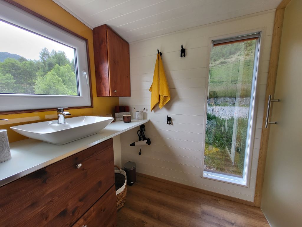Modern bathroom with large window and view of the greenery.