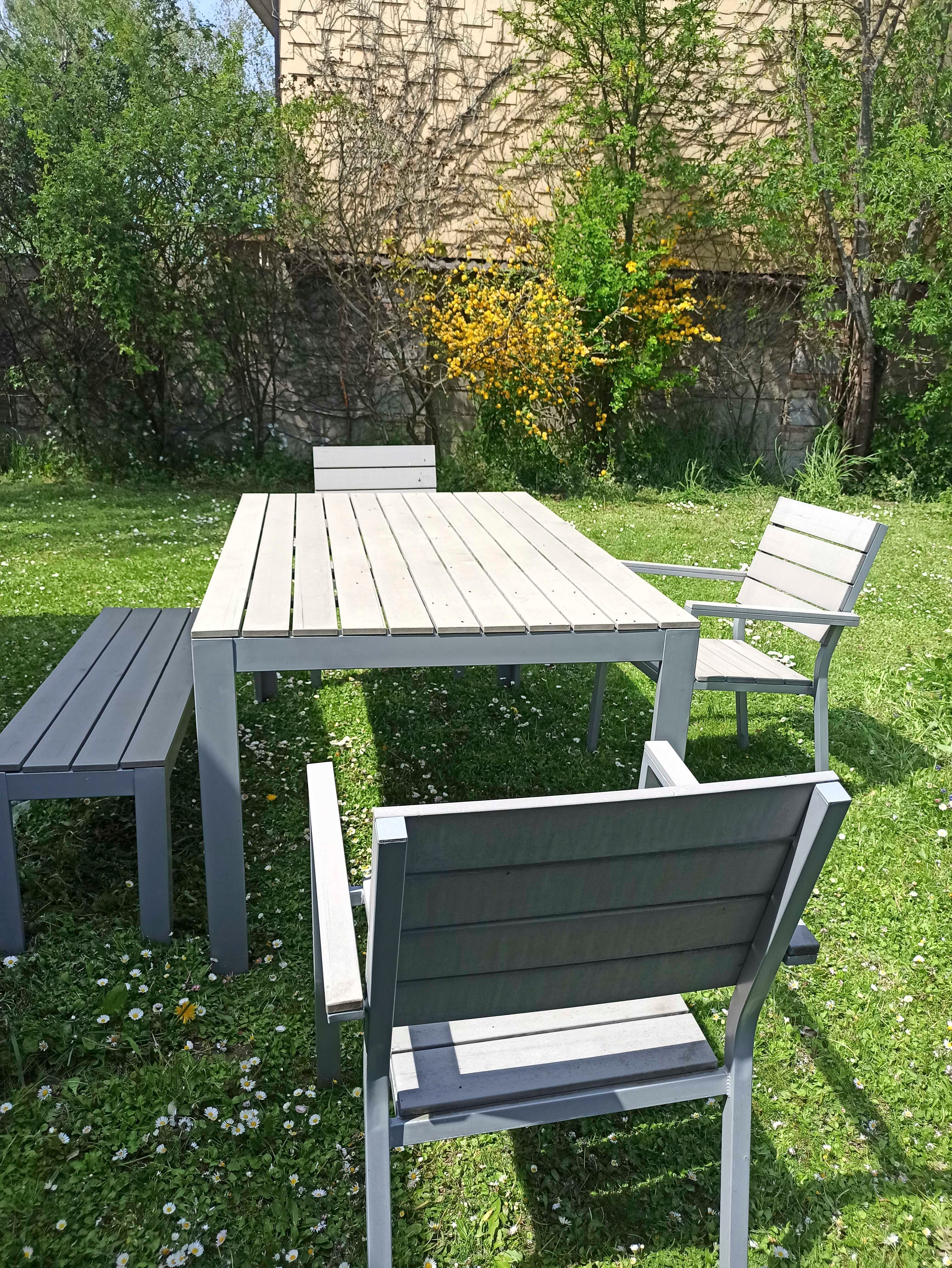Garden furniture set with table, chairs and bench on a lawn.