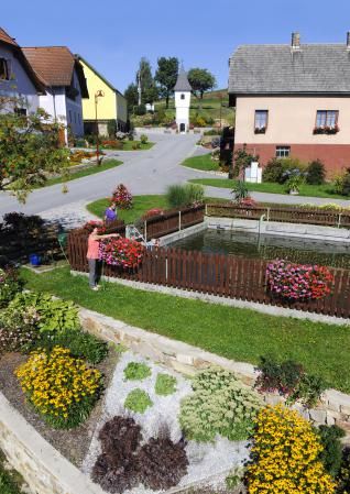 A well-kept garden with flower beds and a small pond in a village.
