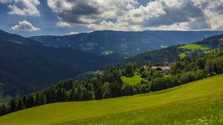 Green hills and forests in a mountainous landscape under a cloudy sky.