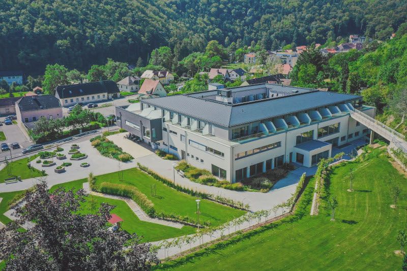 Aerial view of a modern building with garden and surrounding landscape.