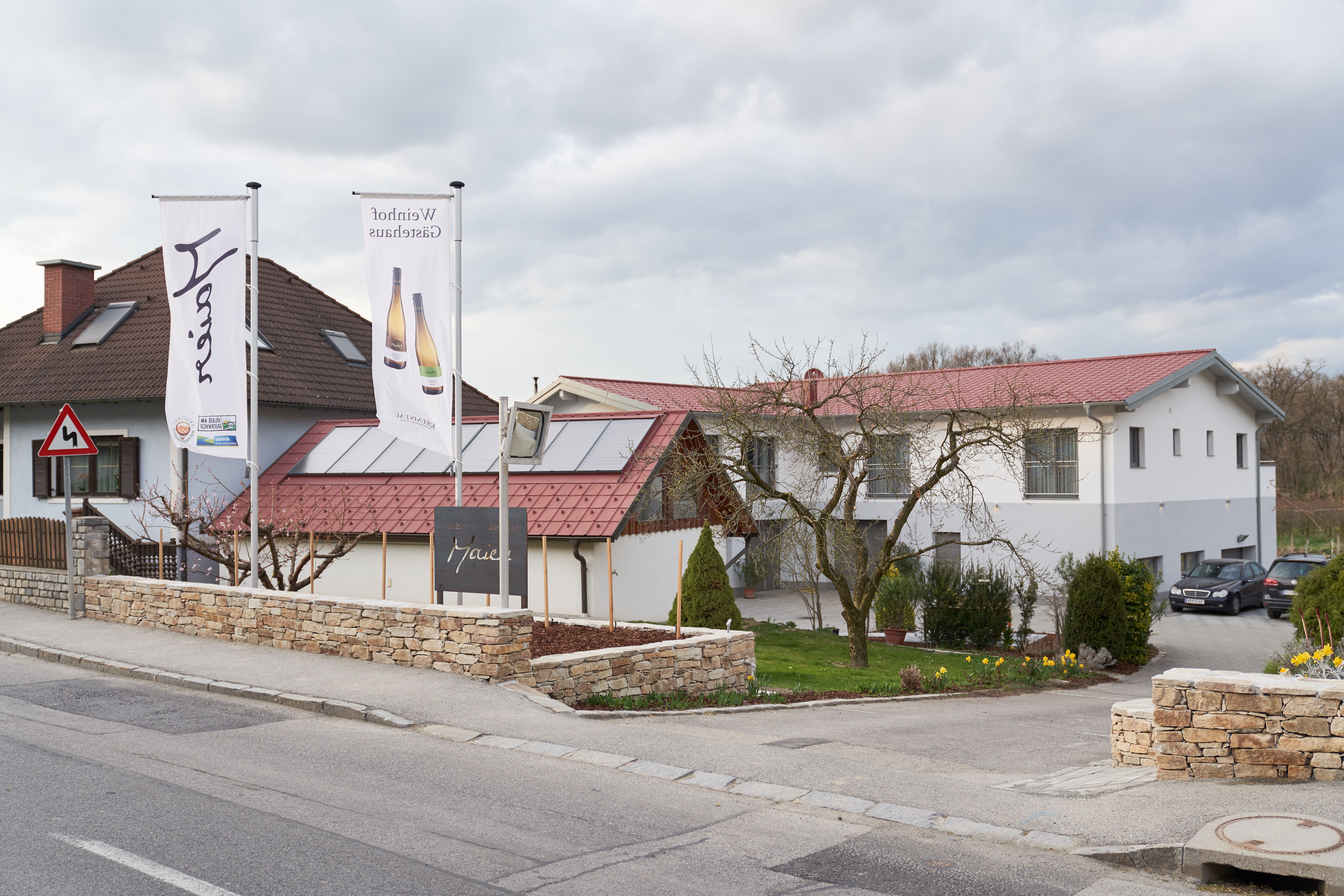 Exterior view of a building with red roofs and two flags in front of it.