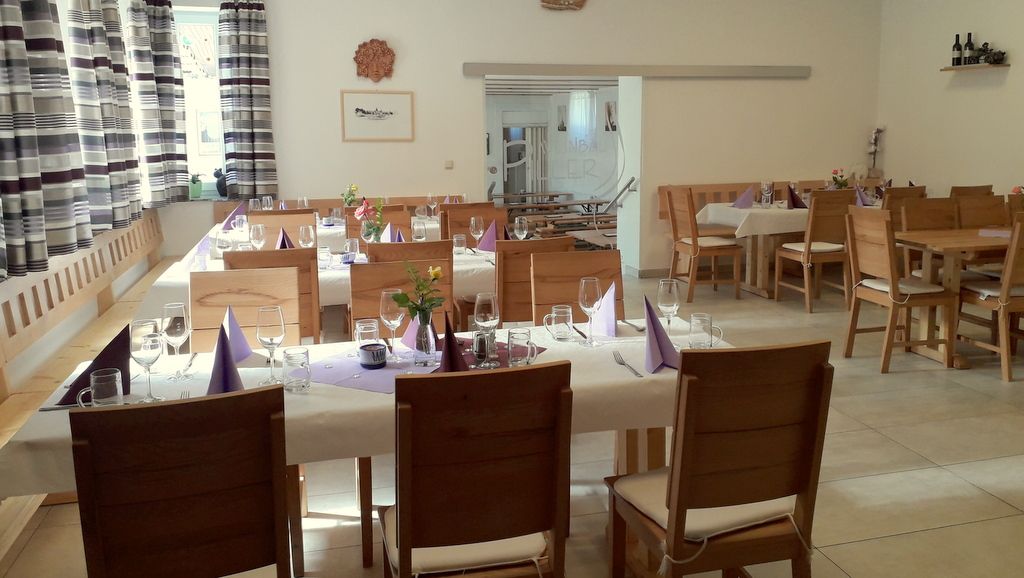 Interior view of a cozy wine tavern with laid tables and wooden furniture.