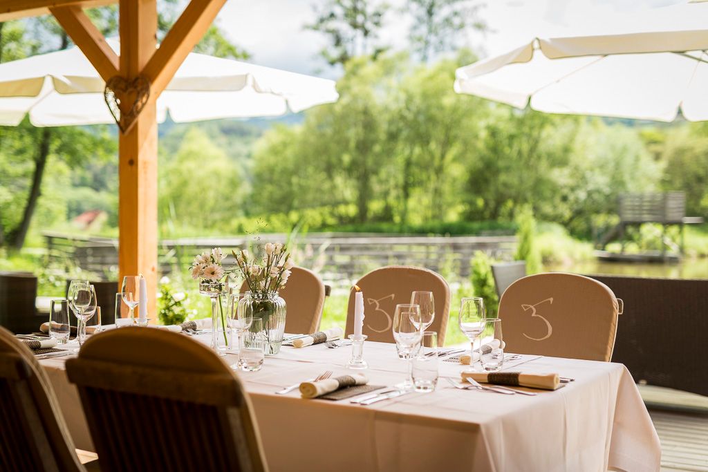 Outdoor table with a view of a pond and trees.