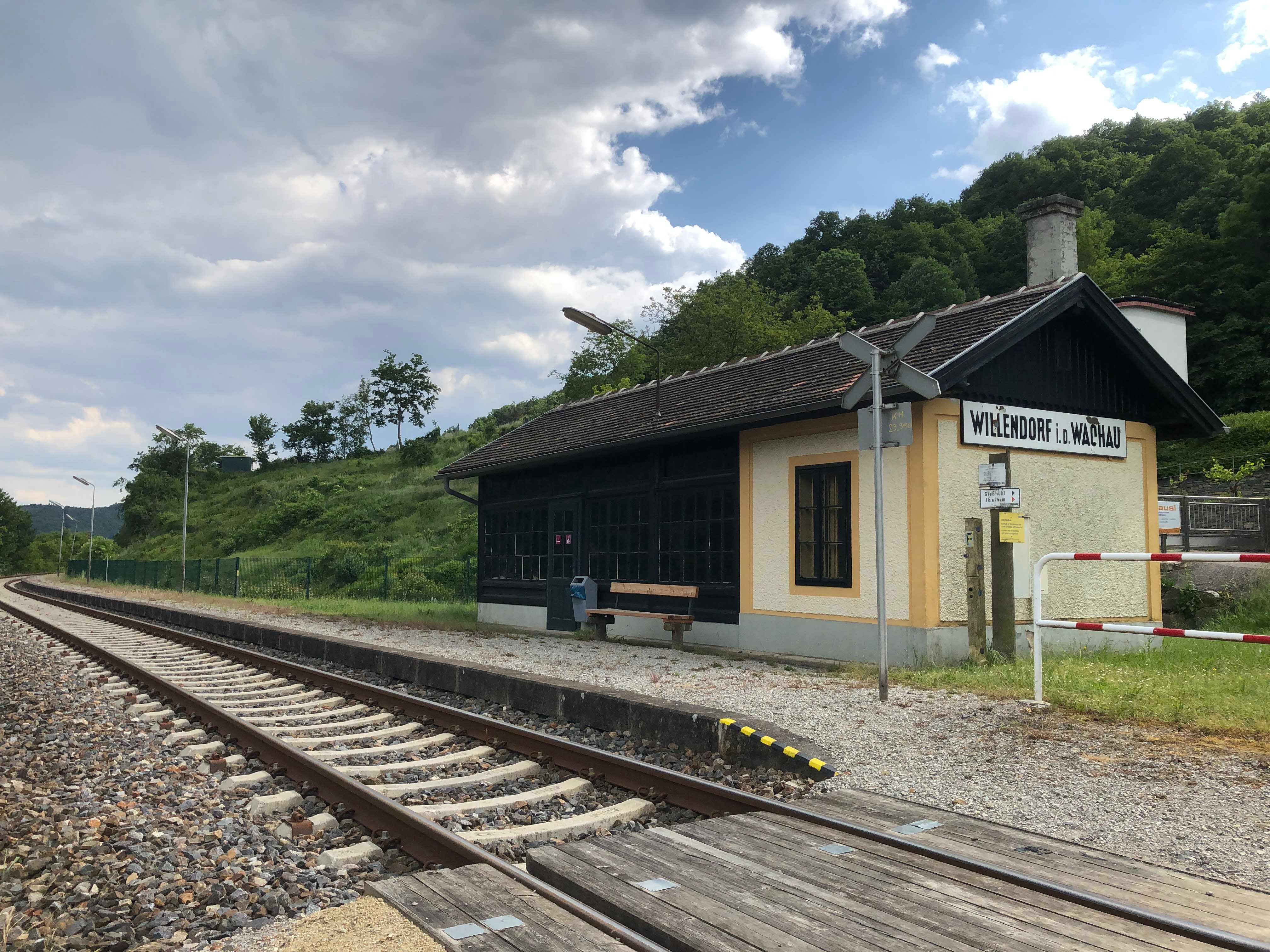 Small station in a rural setting with tracks and a waiting shelter.