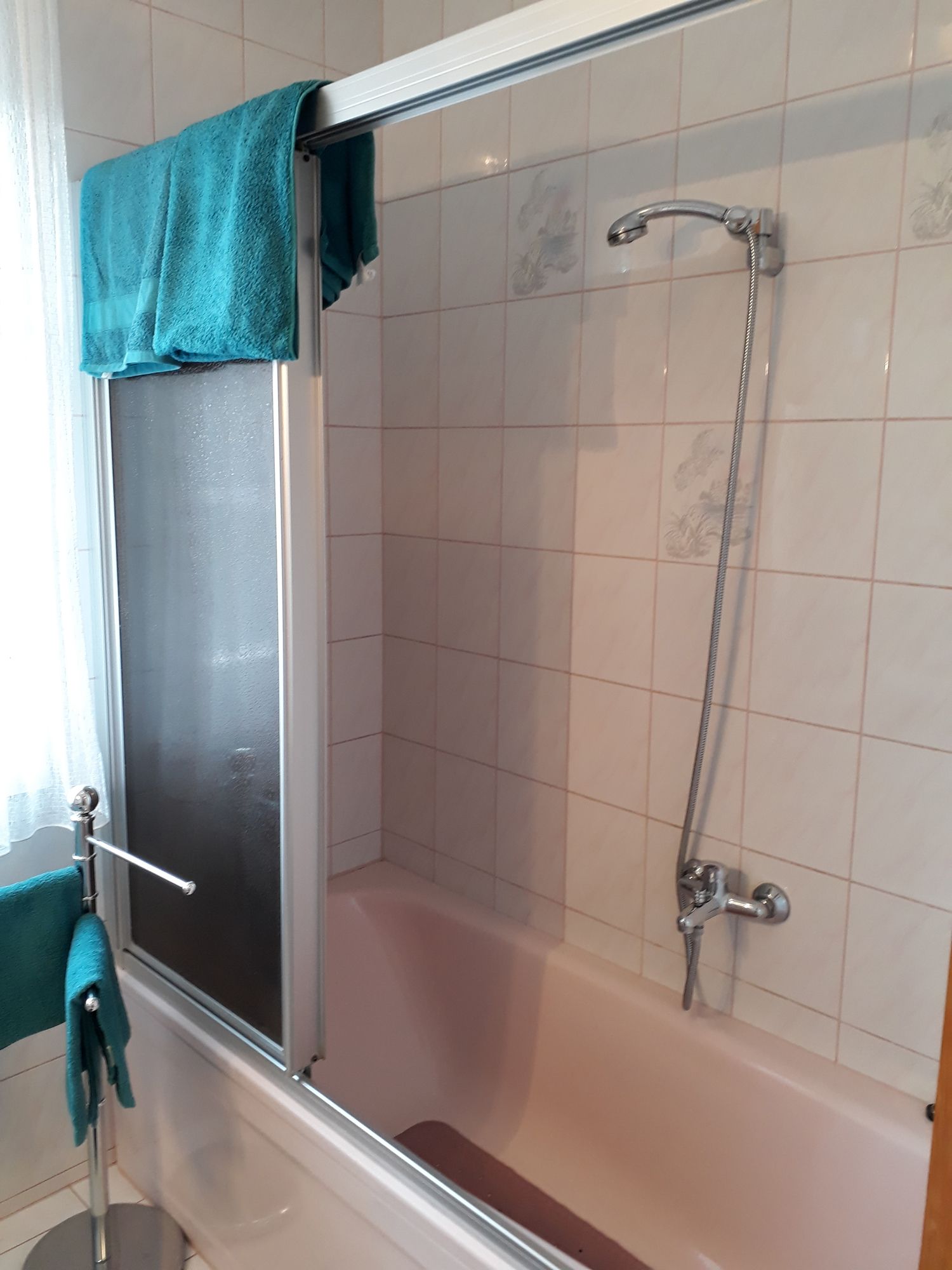 Bathroom with bathtub, shower curtain and blue towels.