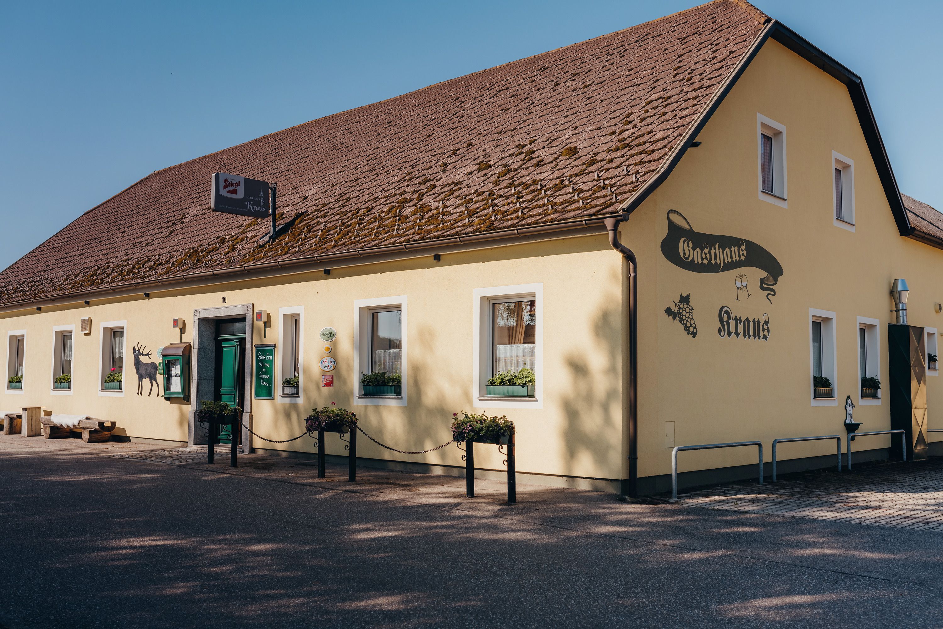 Yellow inn with brown roof and green door, labeled 'Gasthaus Kraus'.