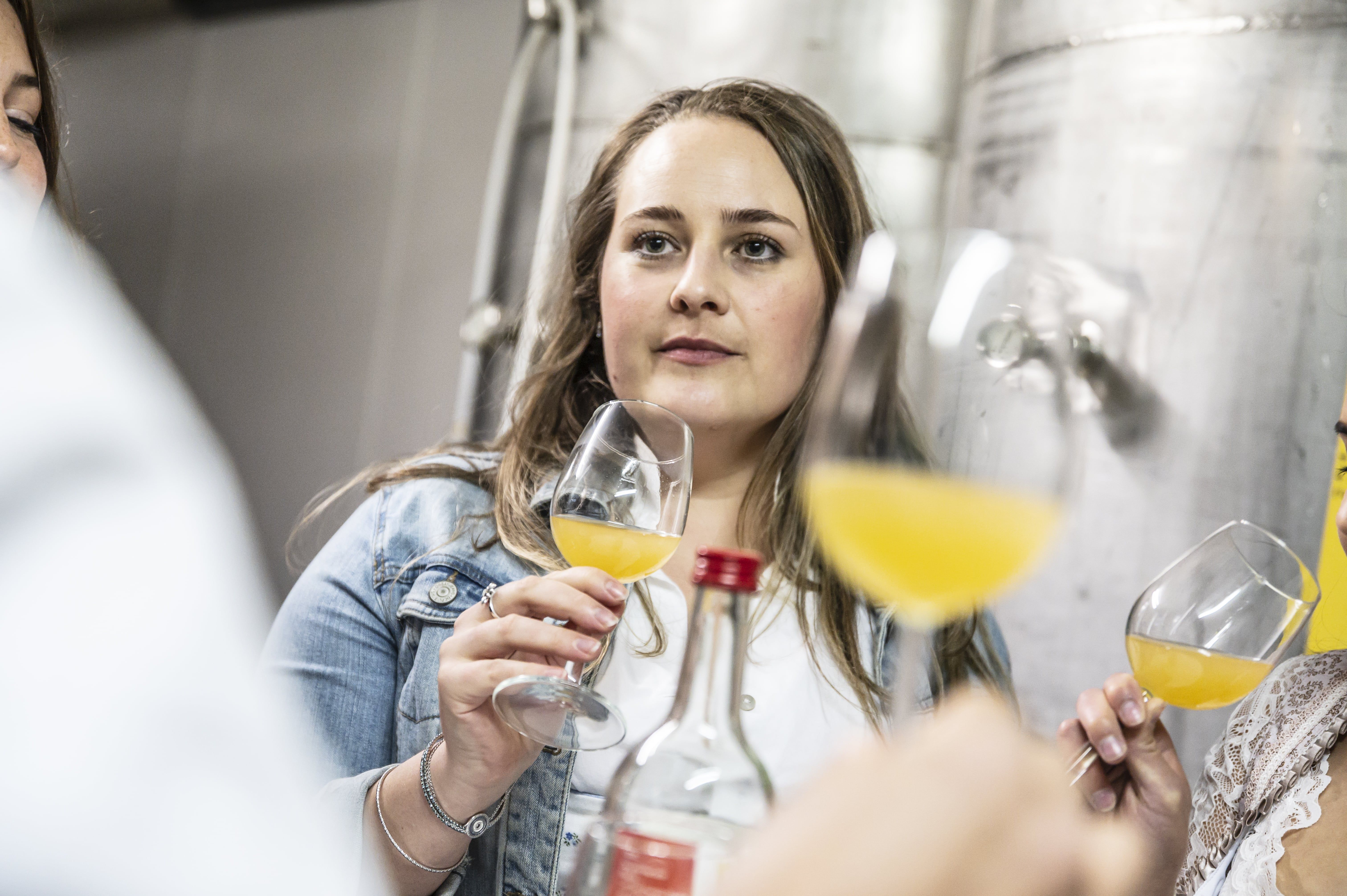 Woman at a cider tasting with glass in hand.