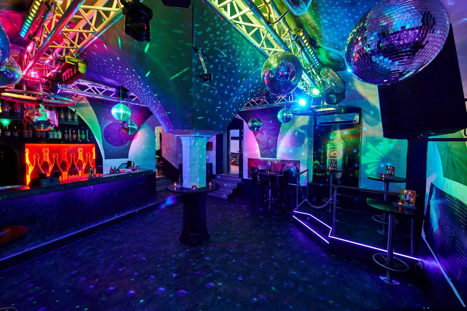 Interior view of a club with disco balls and colorful lighting.
