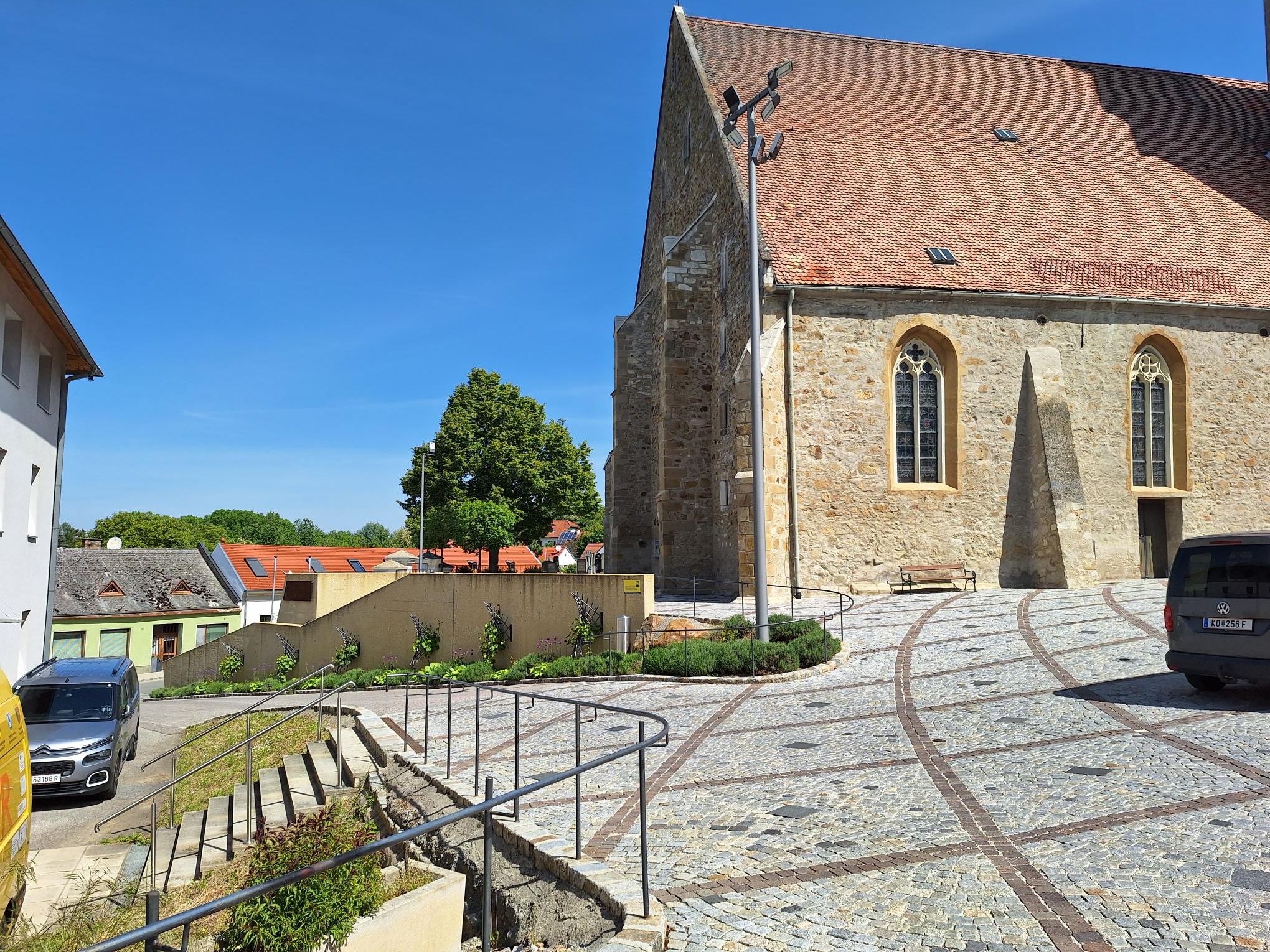 Stone staircase leads to a historic building with a red tiled roof and Gothic windows.