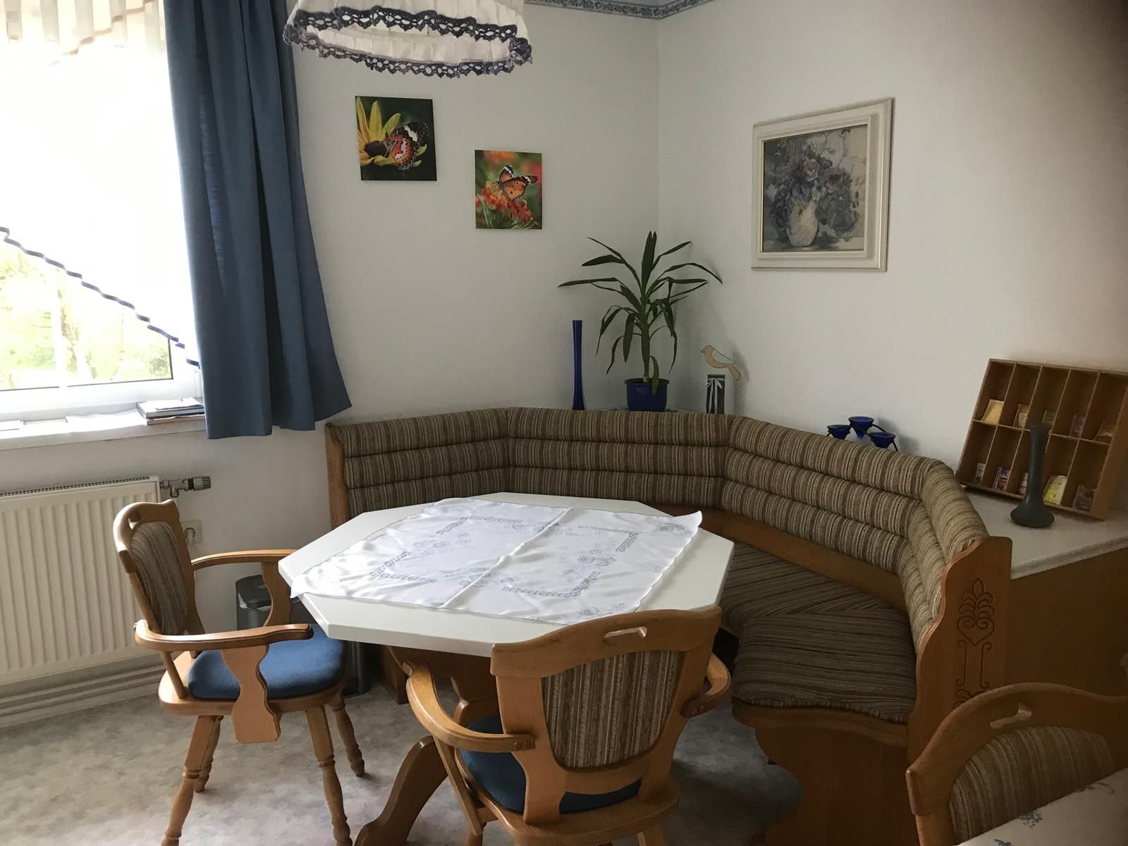 Corner bench in a kitchen with table and chairs, decorated with plants and pictures on the wall.