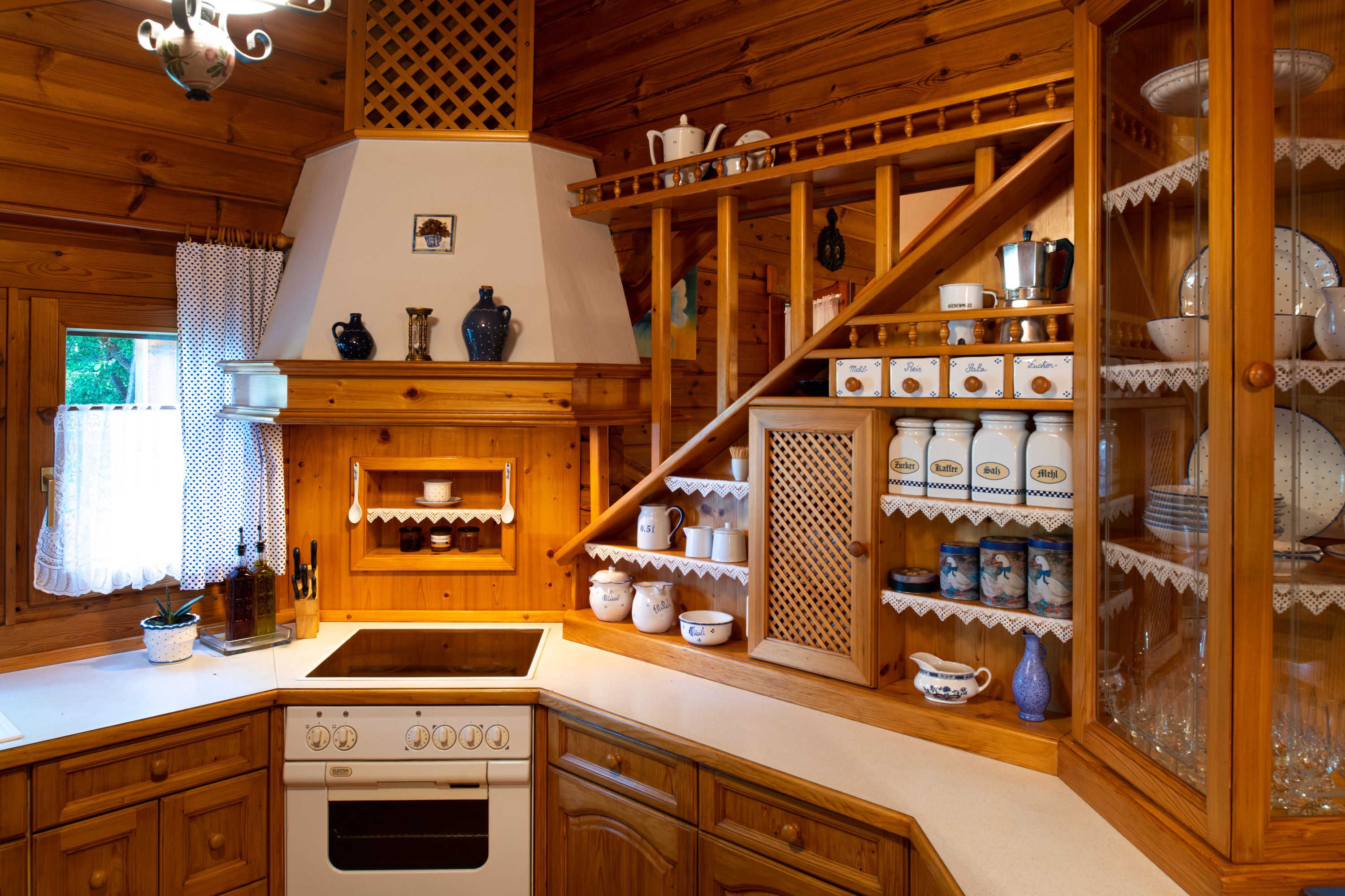 Rustic wooden kitchen with shelves, crockery and spice containers.