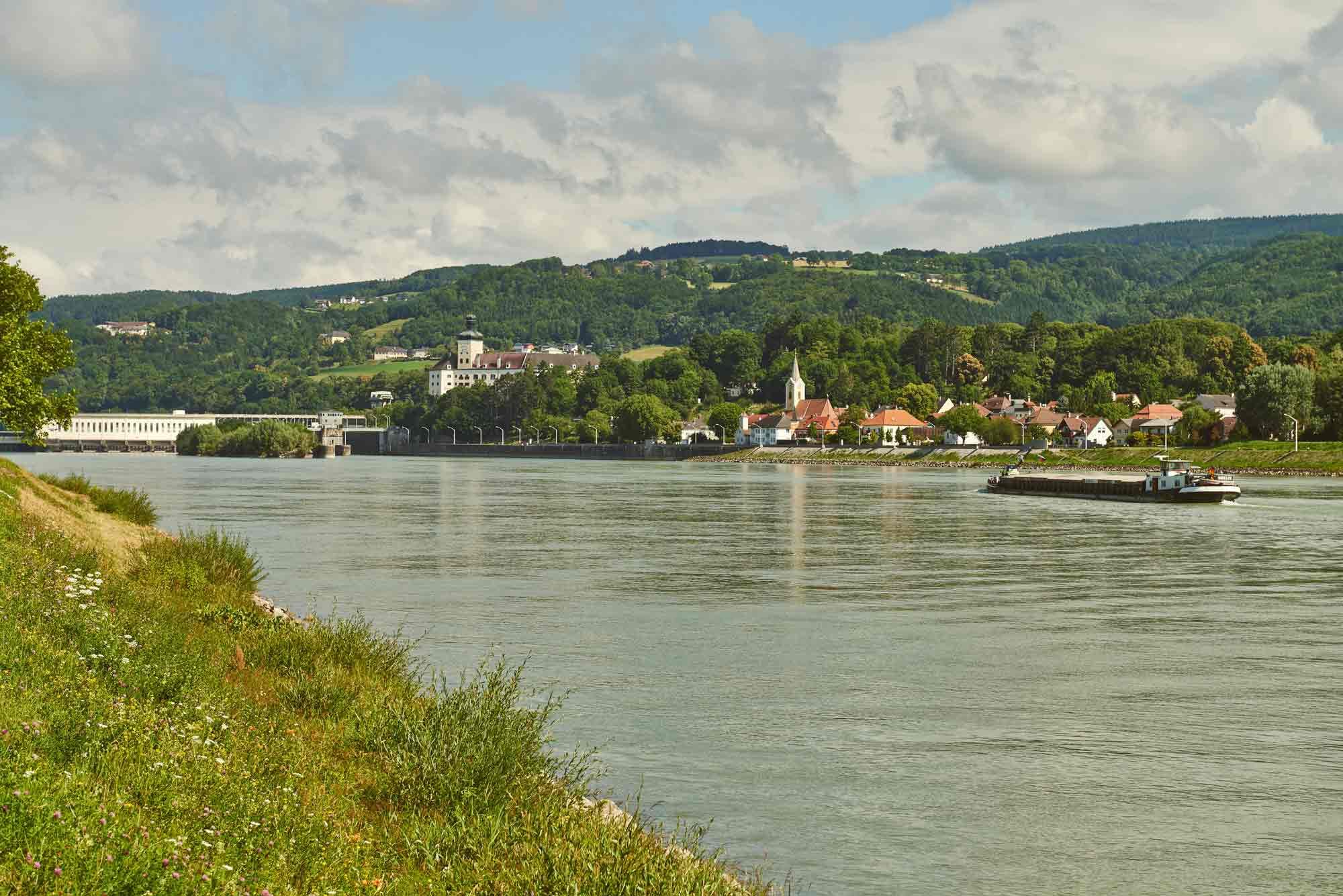 River landscape with village and hills in the background.