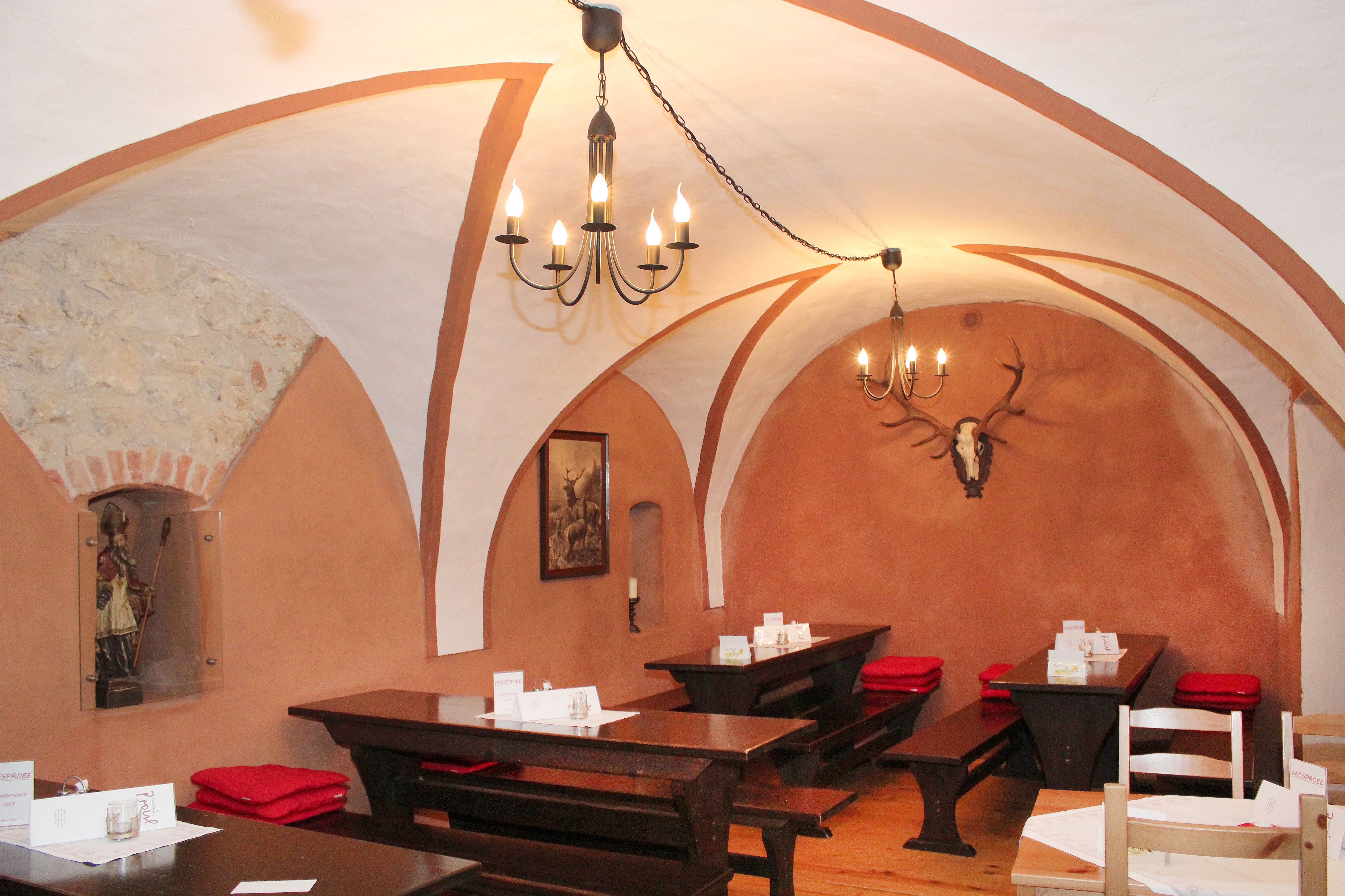 Rustic restaurant with vaulted ceiling, wooden tables and deer antlers on the wall.